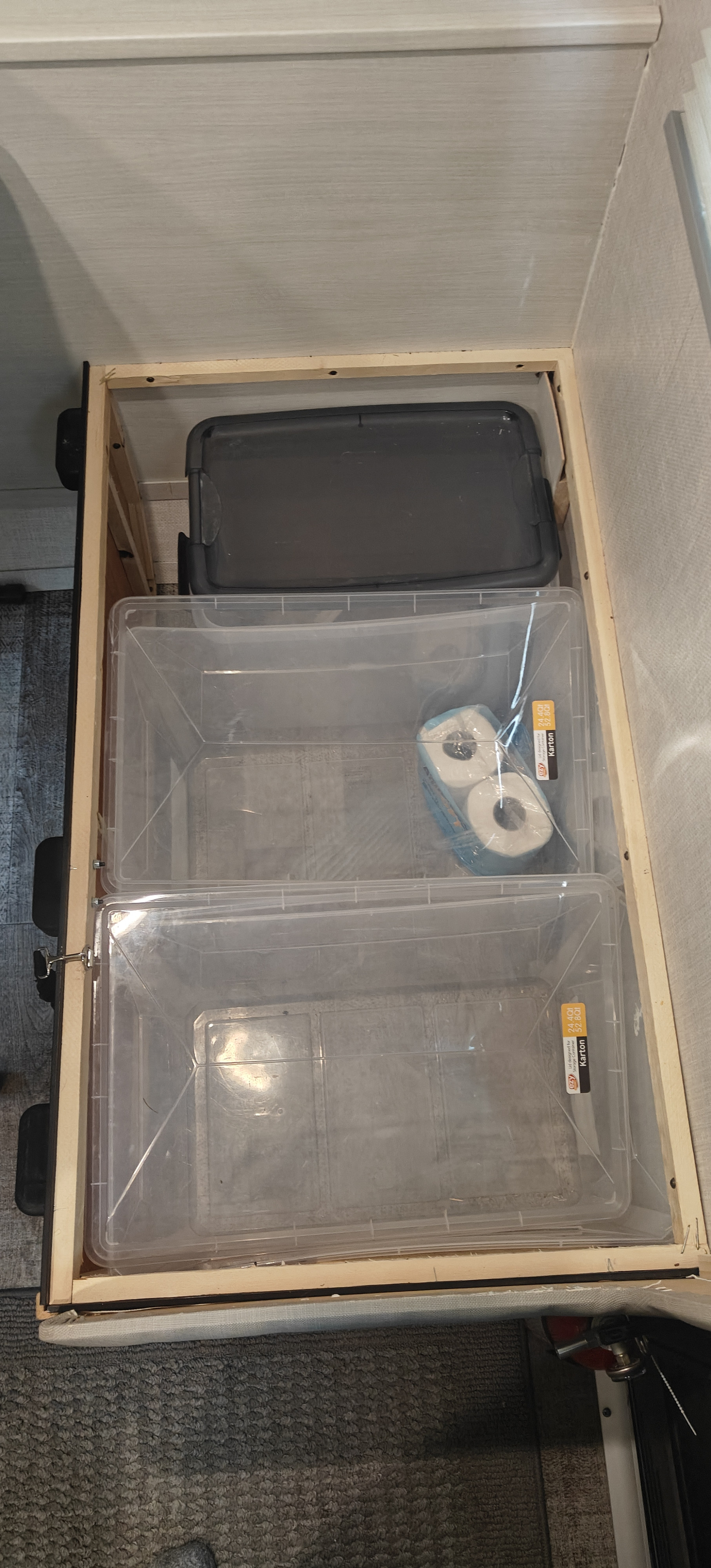 Maximized storage in an RV rental: Two clear bins hold essentials, including toilet paper, within a built-in wooden frame.. Forest River R-Pod 2023
