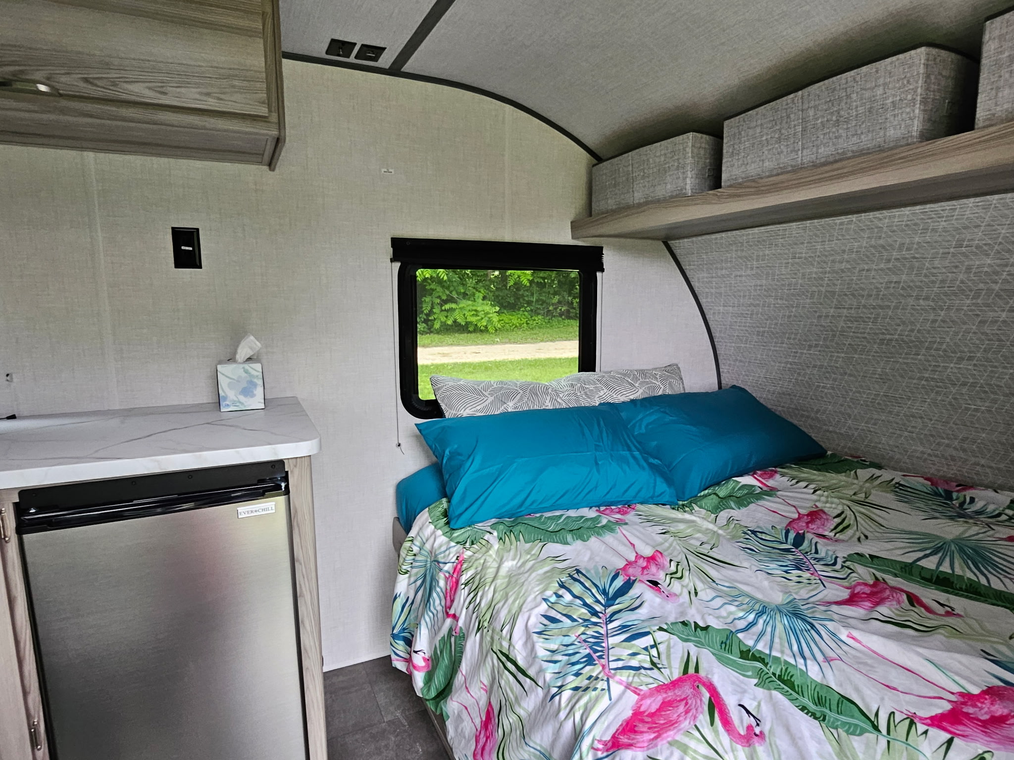 Inside a bright RV rental: features include a tropical flamingo bed, mini-fridge, and ample storage shelves.. Forest River Salem 174dble 2025