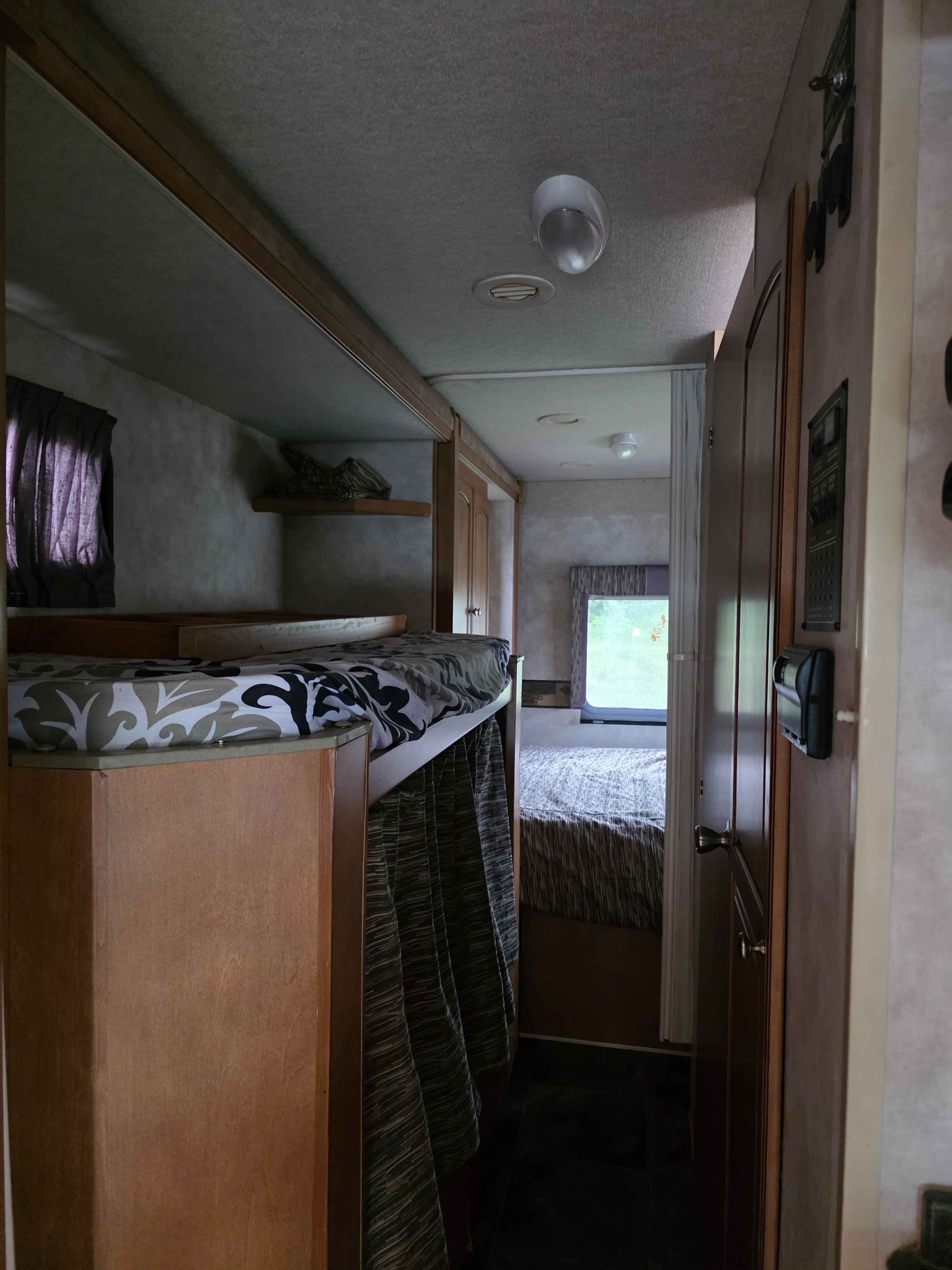 Inside an RV rental: view of bunk beds on left, hallway, and rear bedroom. Functional and compact living space.. Winnebago Chalet 2013