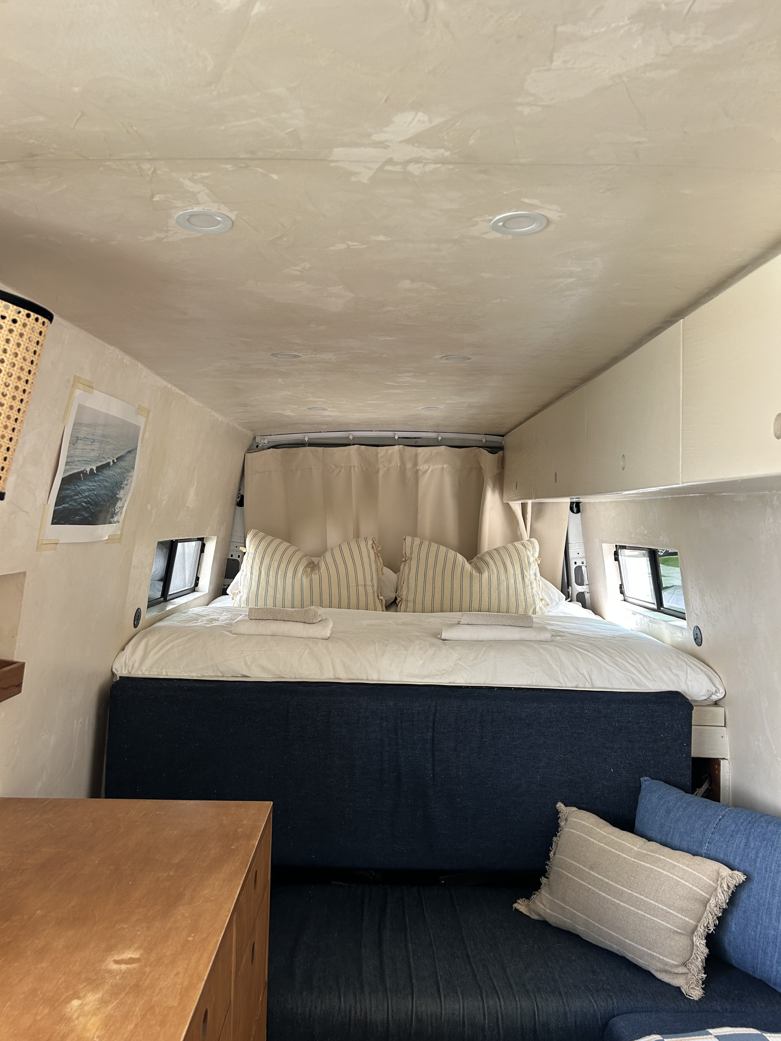 Cozy RV rental interior with a comfortable bed, textured walls, and seating area, perfect for a road trip.. Mercedes-Benz Sprinter RV Motorhome Campervan 2010