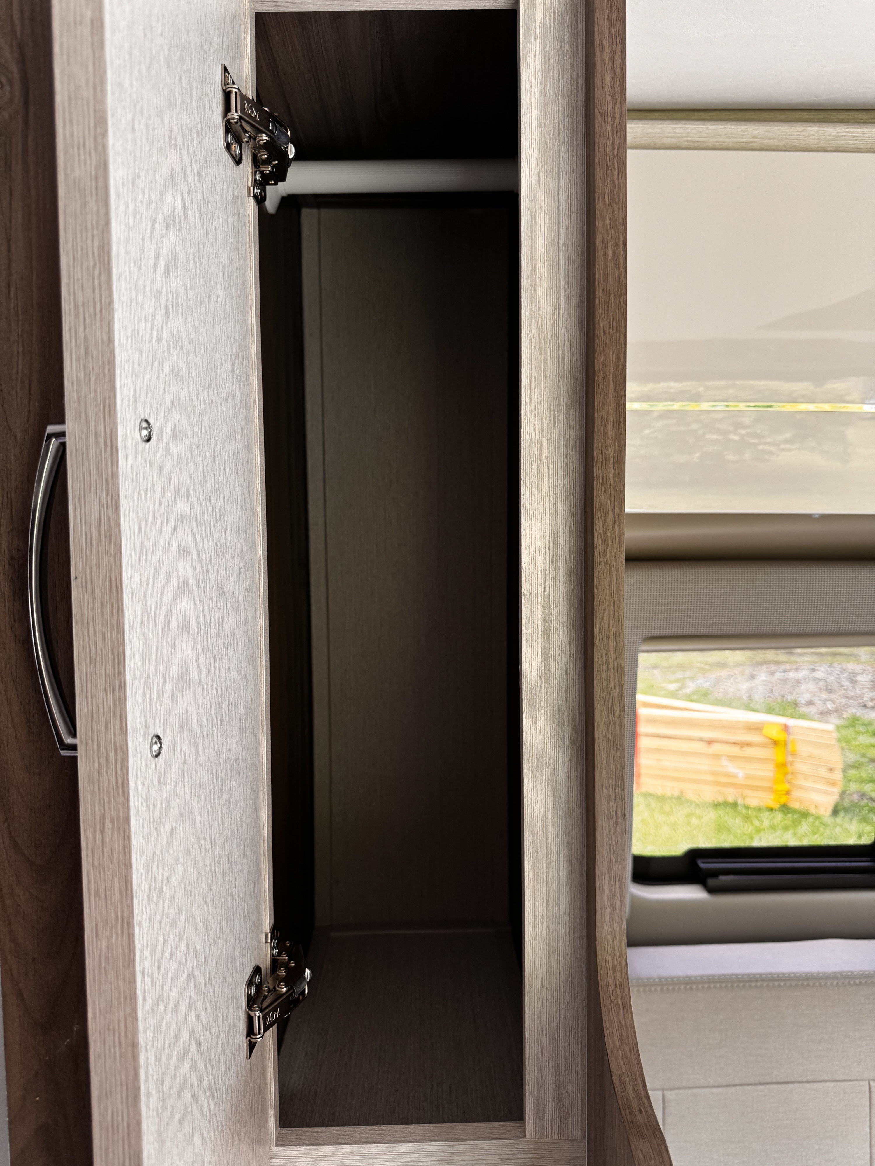 RV rental: Open cabinet reveals hanging rod and window with outdoor view of grass.. Thor Tellaro 2023
