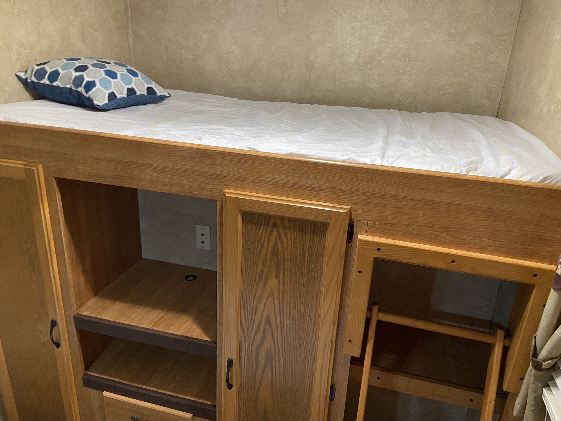Inside an RV rental: a cozy bunk bed with white sheets, patterned pillow, wood cabinetry, and a ladder.. Keystone RV Sprinter 2010