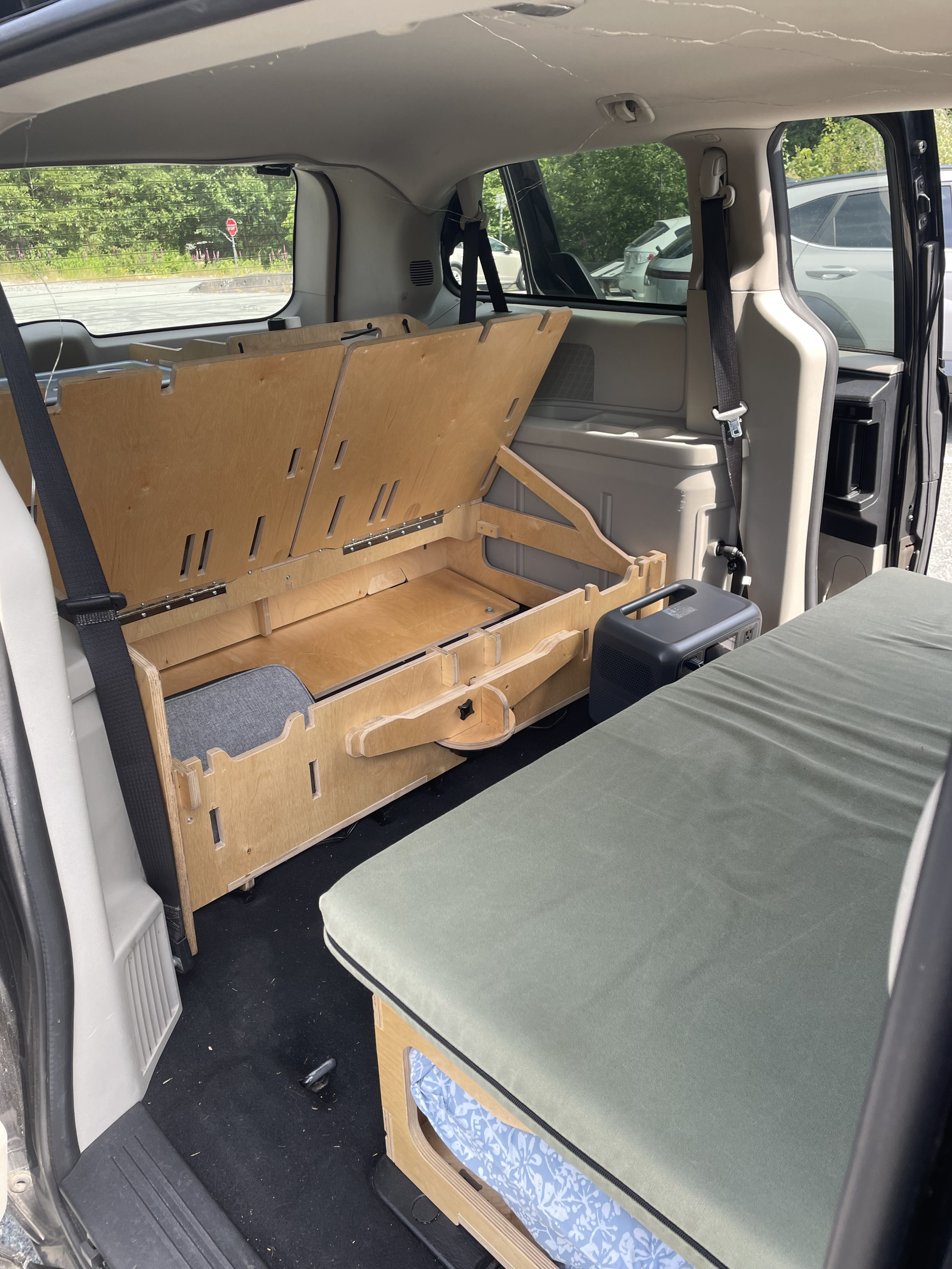 This RV rental features a minivan camper conversion, revealing a clever wooden bed platform, storage, and portable power. Ideal for van life.. Dodge Grand Caravan 2014
