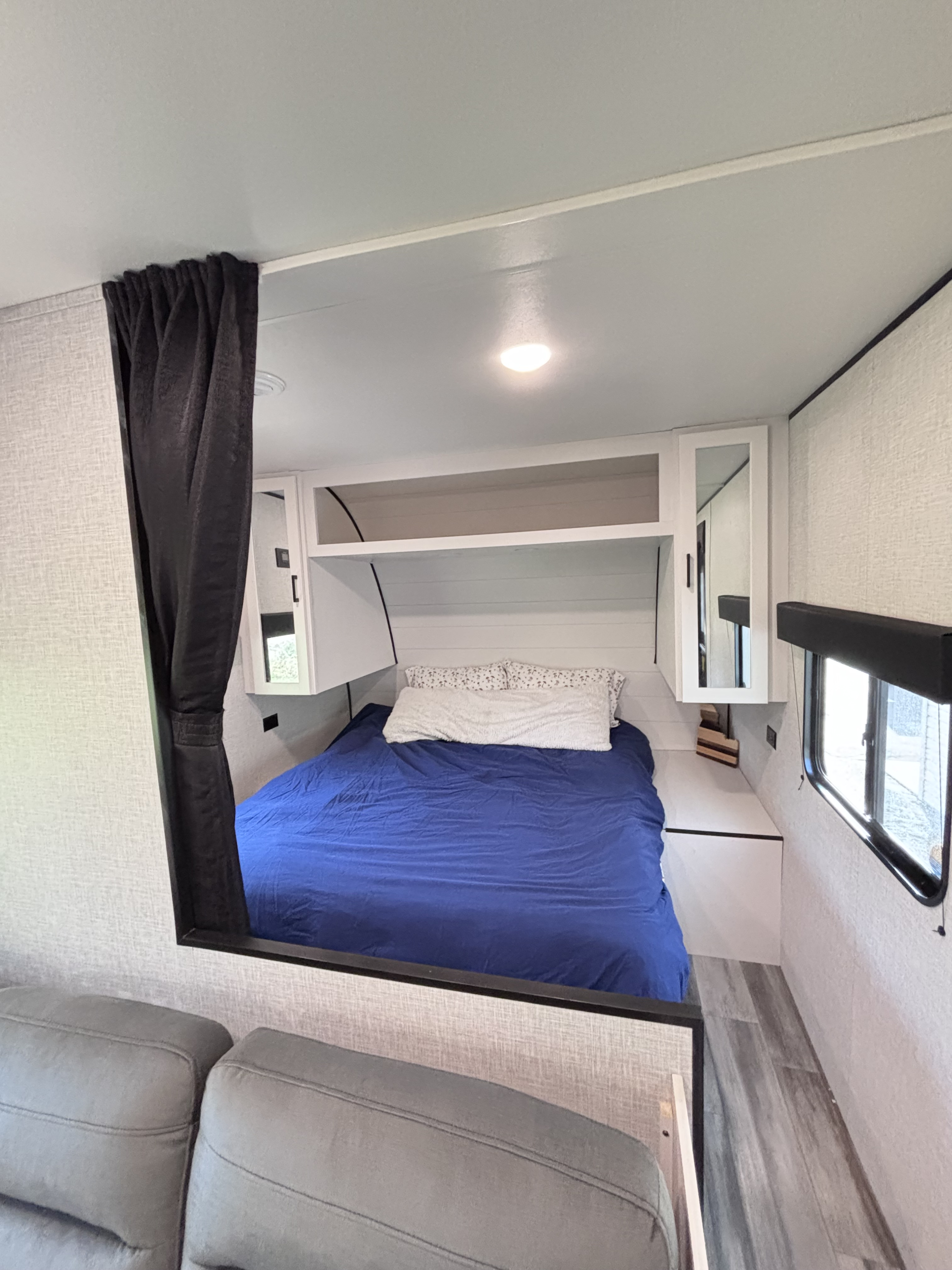 Inside an RV rental: a modern bedroom featuring a bed with blue bedding, white cabinets, and a privacy curtain.. Jayco Jay Flight slx 260 bhw 2025