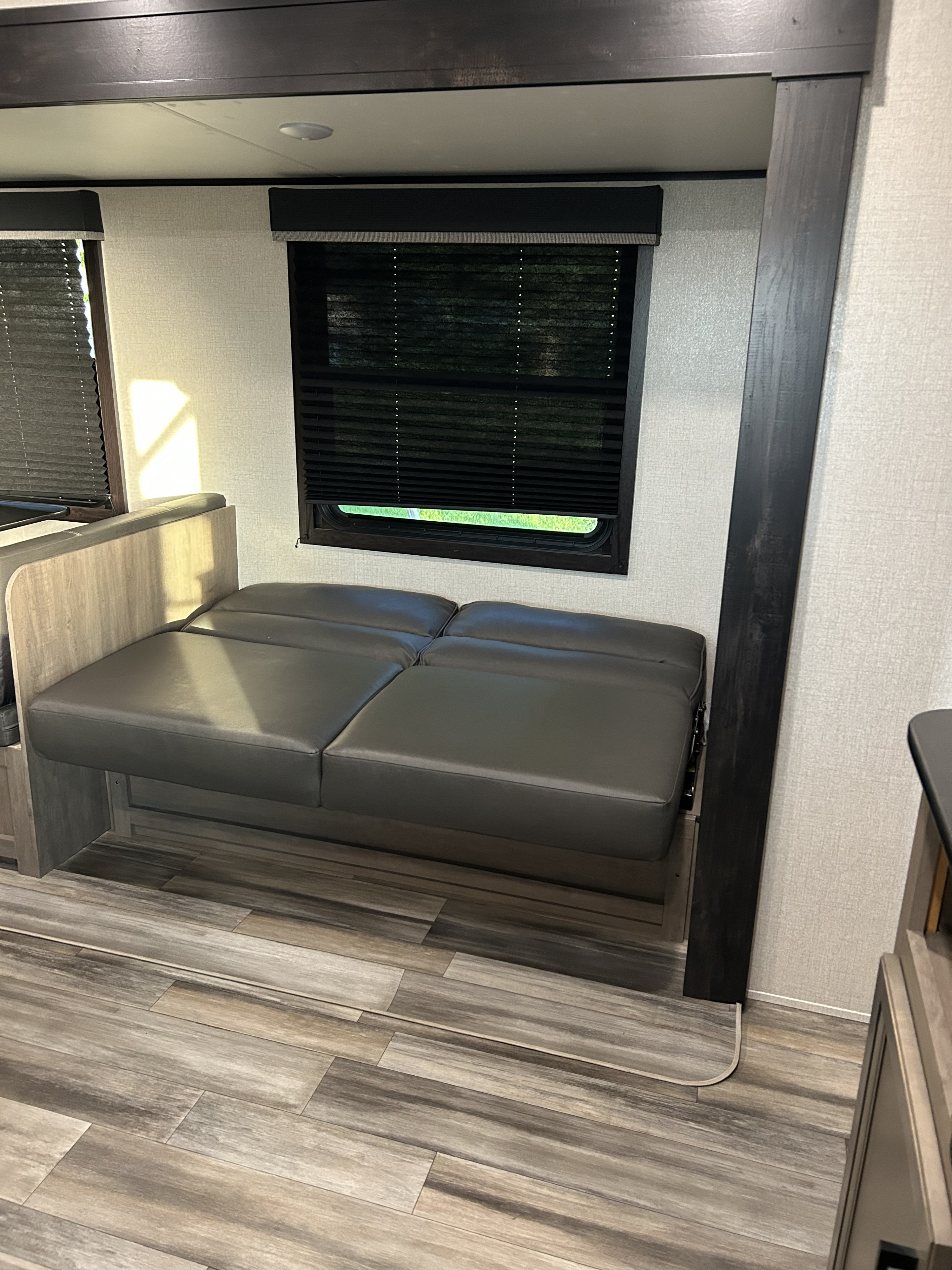 RV rental interior: A gray convertible sofa-bed, windows with blinds, and laminate flooring.. Starcraft Autumn Ridge 2022