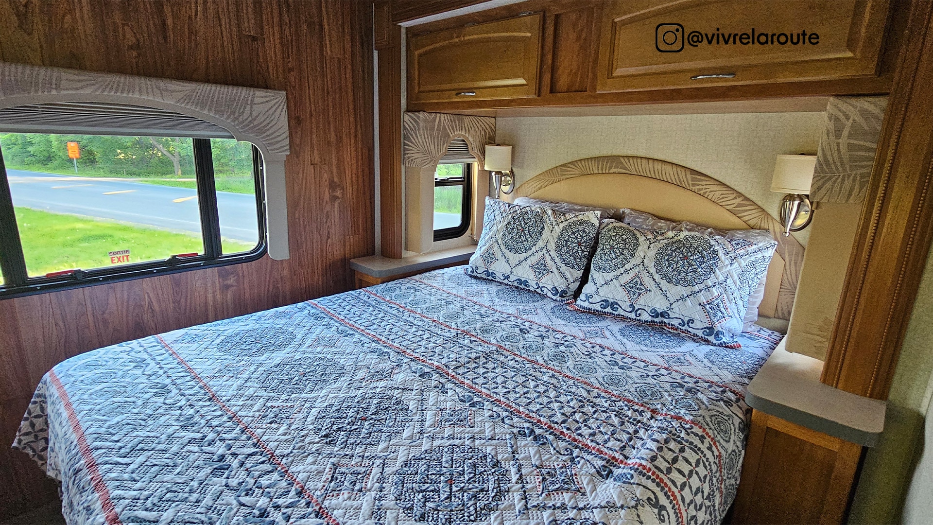 Explore comfort in this RV rental bedroom: a cozy bed with patterned bedding, bedside lamps, and a view of the road.. Tioga SL 2008