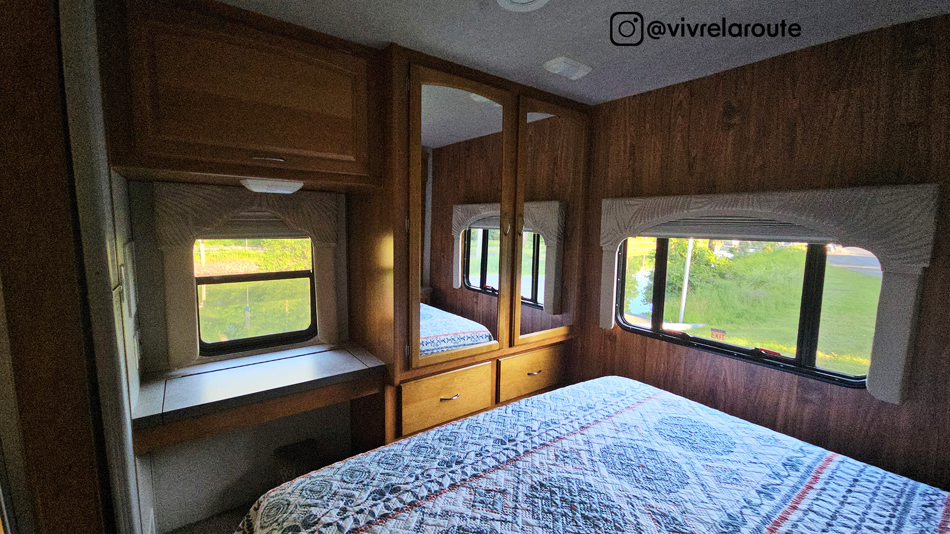 Inside your next RV rental: a bright bedroom with a quilt-covered bed, wood paneling, and mirrored wardrobe for comfortable travel.. Tioga SL 2008