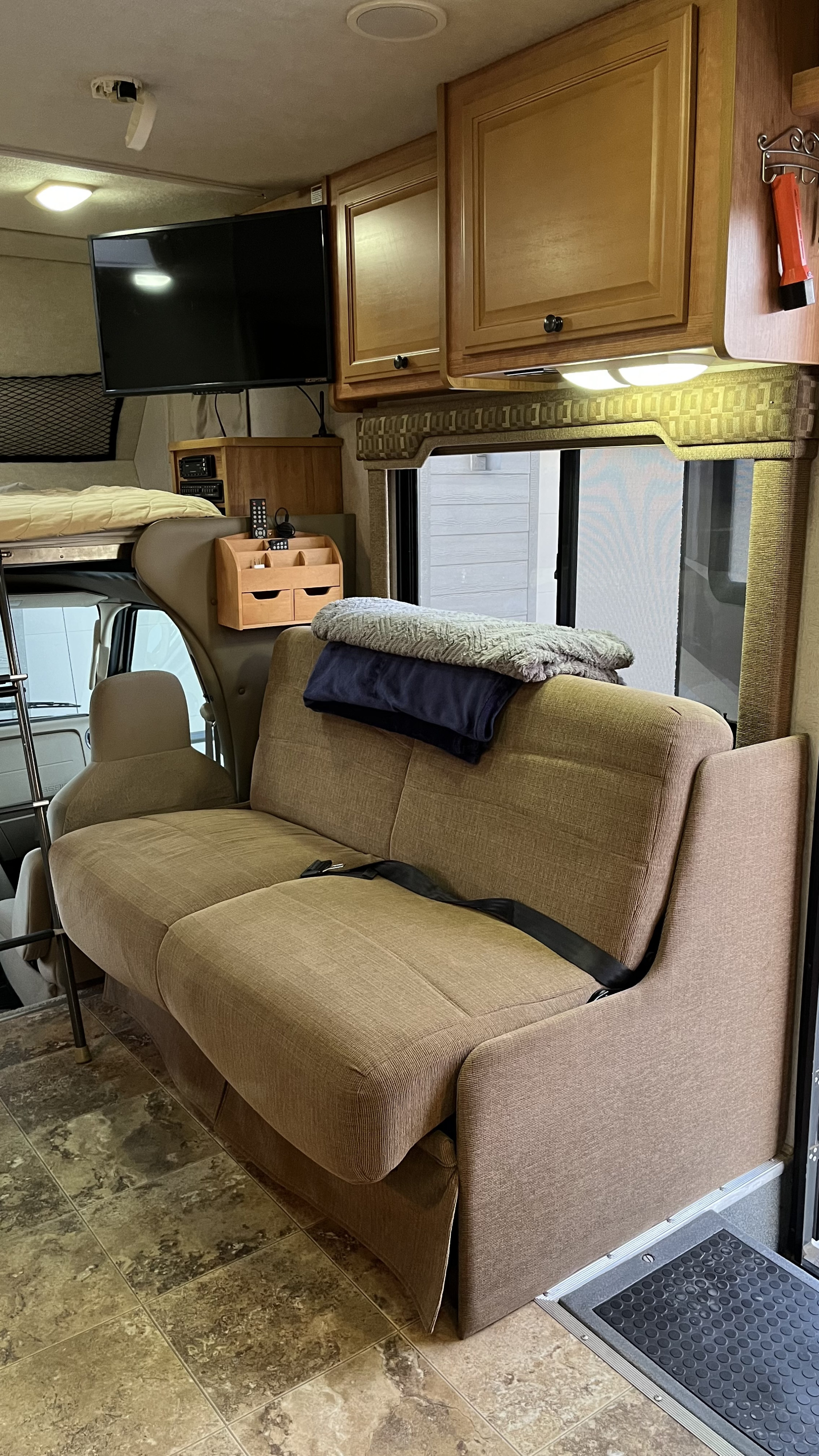 Spacious rv rental living area with a comfy brown sofa, bunk bed, flat-screen TV, and wooden cabinets.. Jamboree Jamboree Motorhome 2010