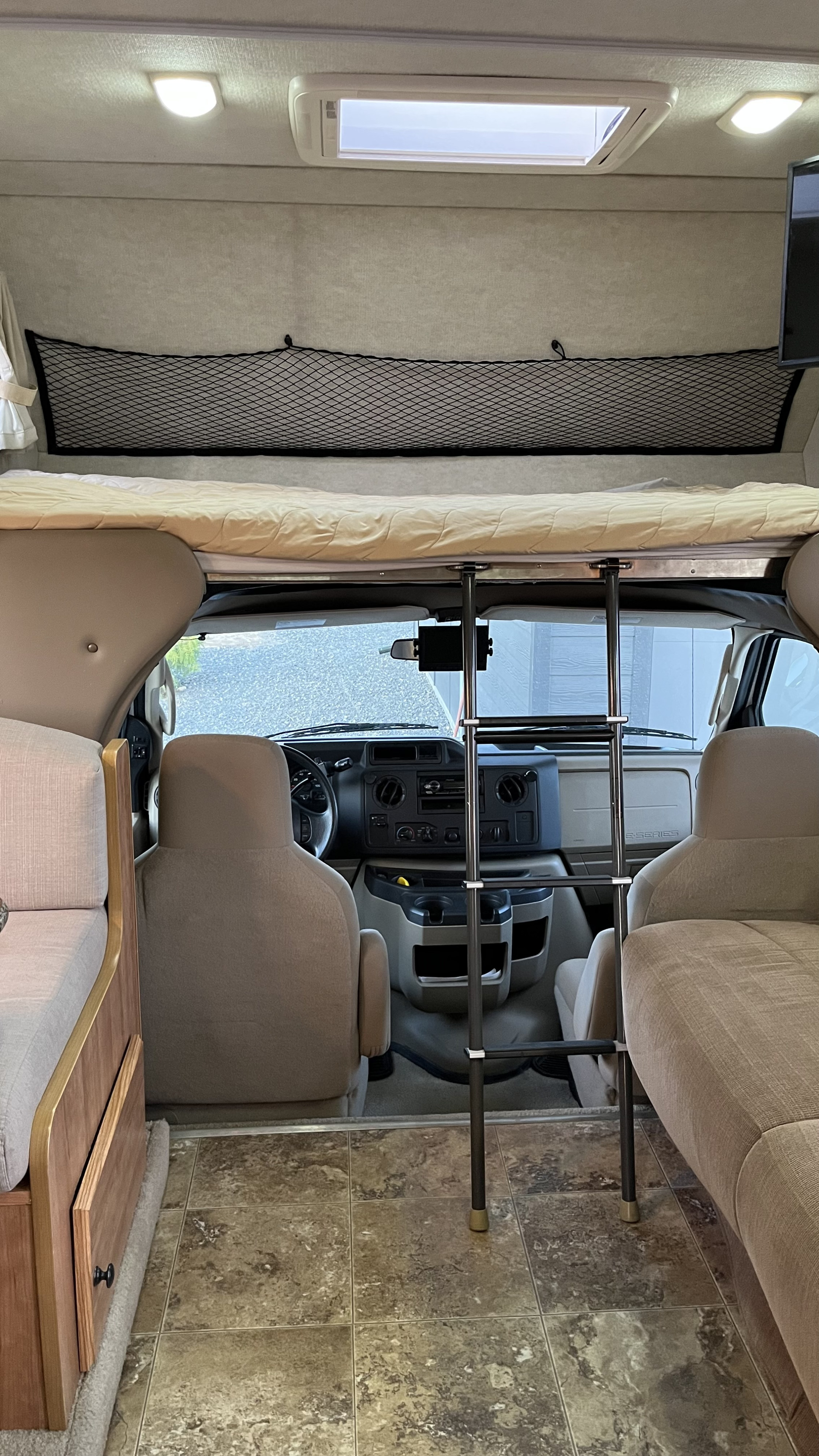 RV rental interior: an overhead bunk with ladder, front cab, and side seating. Functional and ready for your next trip.. Jamboree Jamboree Motorhome 2010