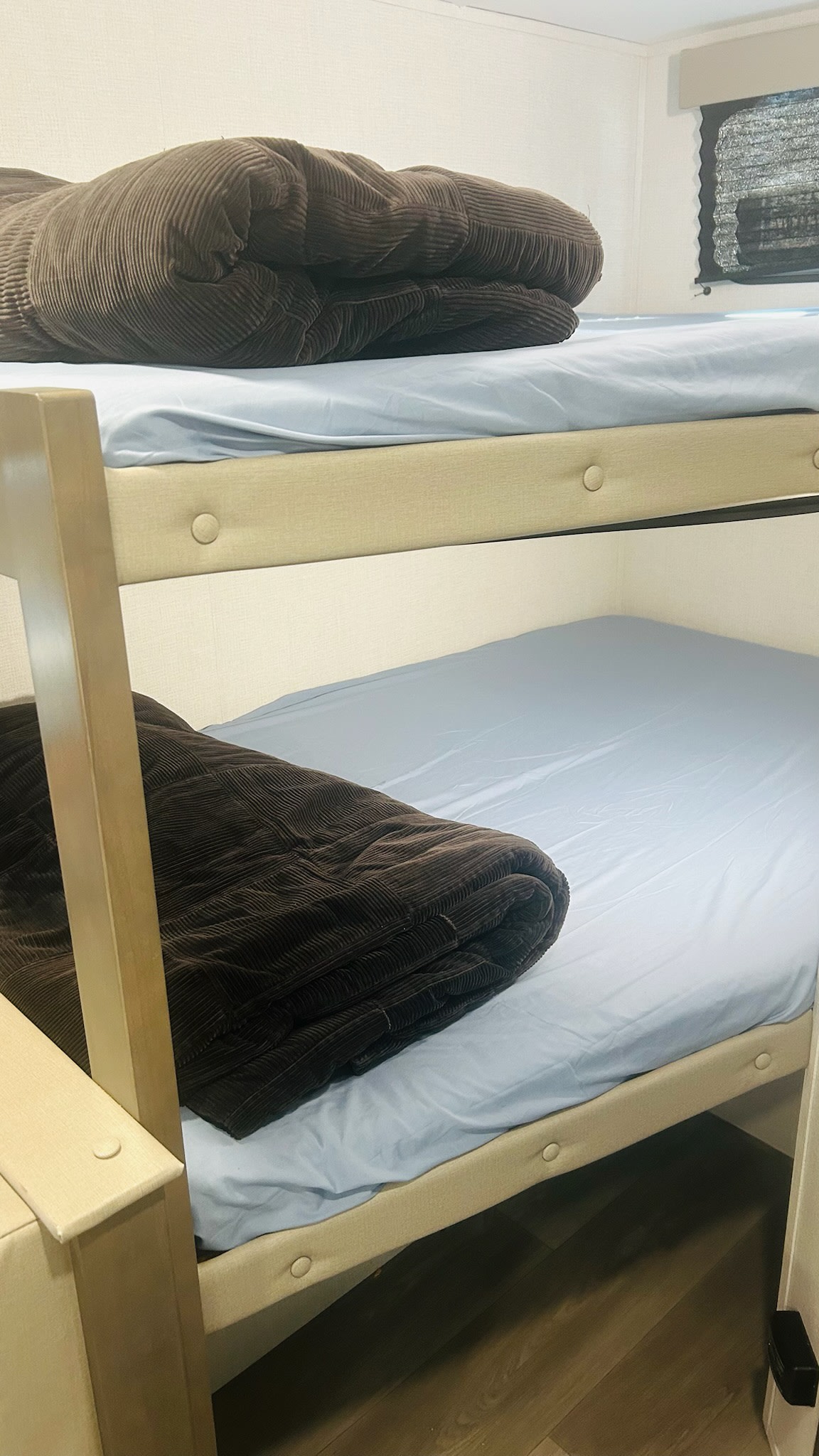 RV rental sleeping area: two bunk beds, each with light blue sheets and folded brown corduroy blankets.. Grand Design Transcend 2025