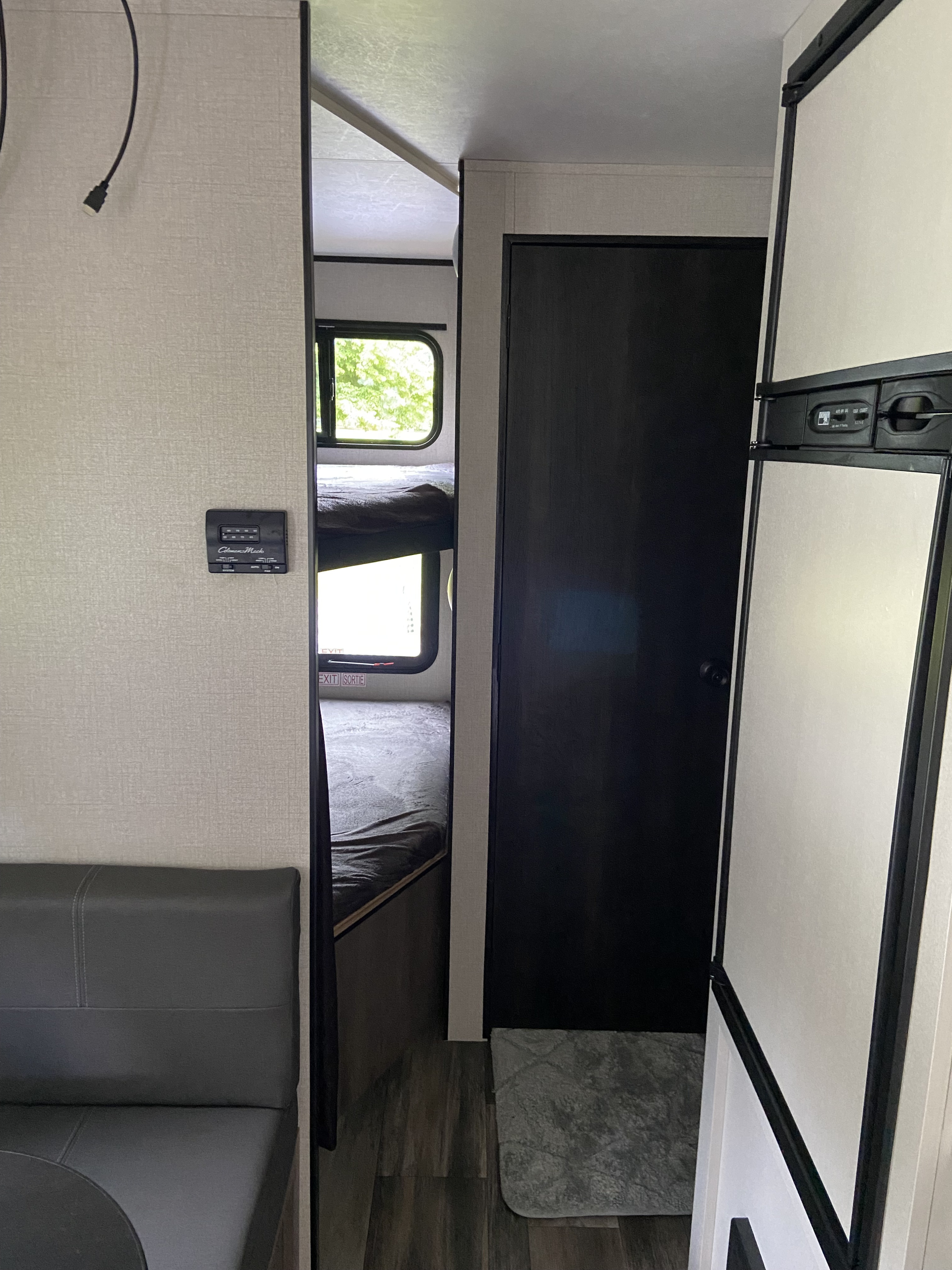 Interior of an RV rental, showcasing bunk beds, a dark door, refrigerator, and a dinette, perfect for family travel.. Highland Ridge RV Open Range 2020