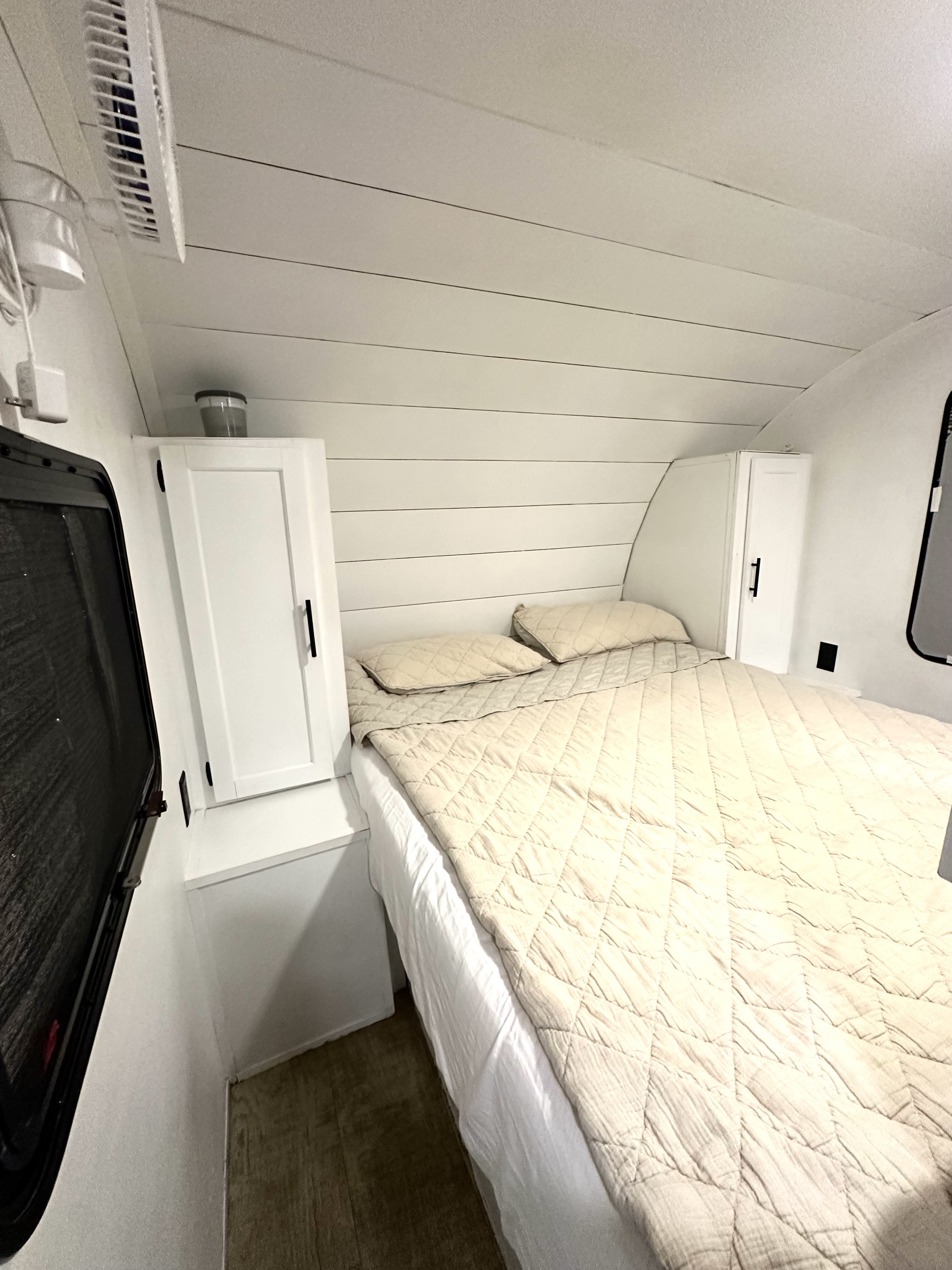 This RV rental offers a compact and comfortable bedroom with white shiplap walls, a soft bed, and side cabinets.. Gulf Stream Trailmaster 2018