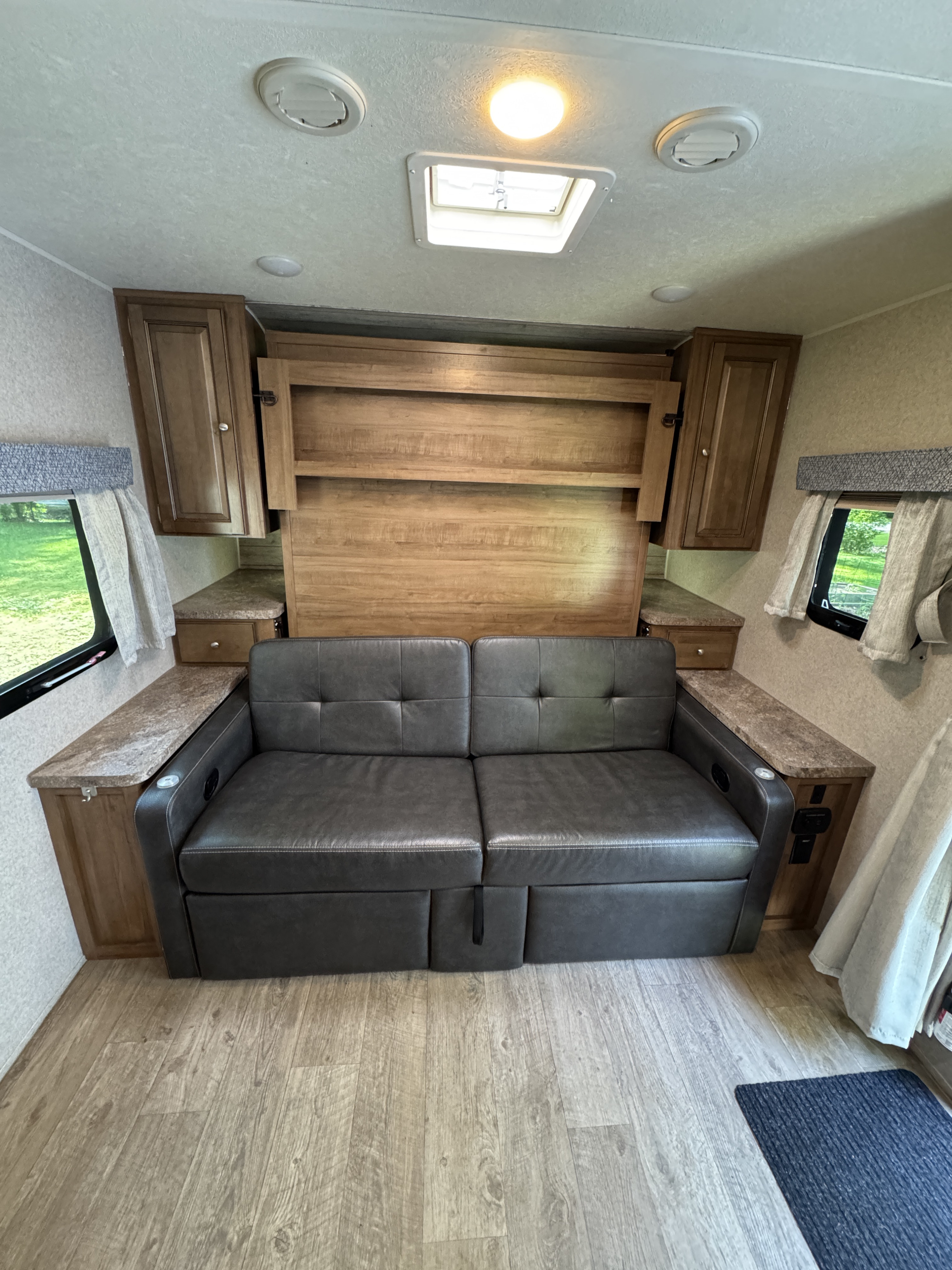 Comfortable RV rental interior featuring a convertible sofa bed, overhead cabinets, and compact living space.. Forest River Rockwood Mini Lite 2019