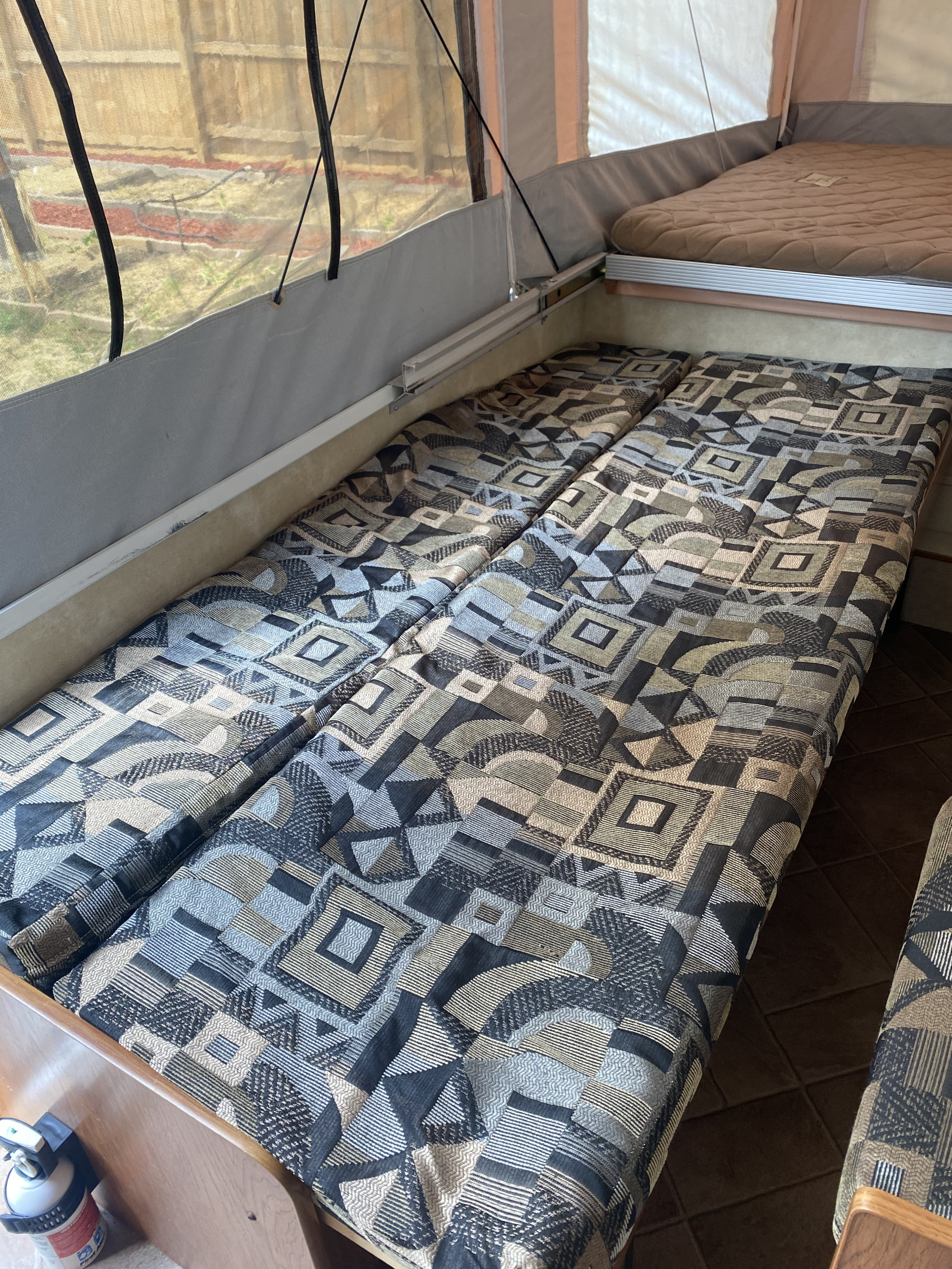 RV rental interior: A pop-up camper's raised bed and lower seating with patterned cushions converted to a bed area.. Coachmen Clipper Sport 108ST 2012