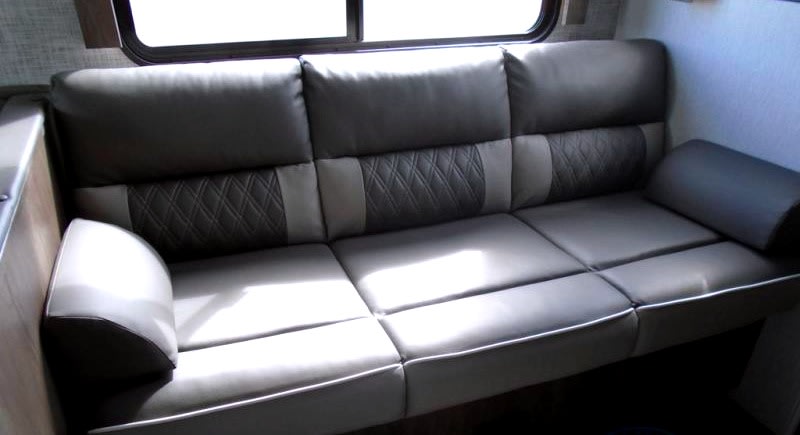 Spacious RV rental interior features a comfortable three-seat sofa with stylish patterned back cushions and armrests.. Forest River Evo 2022