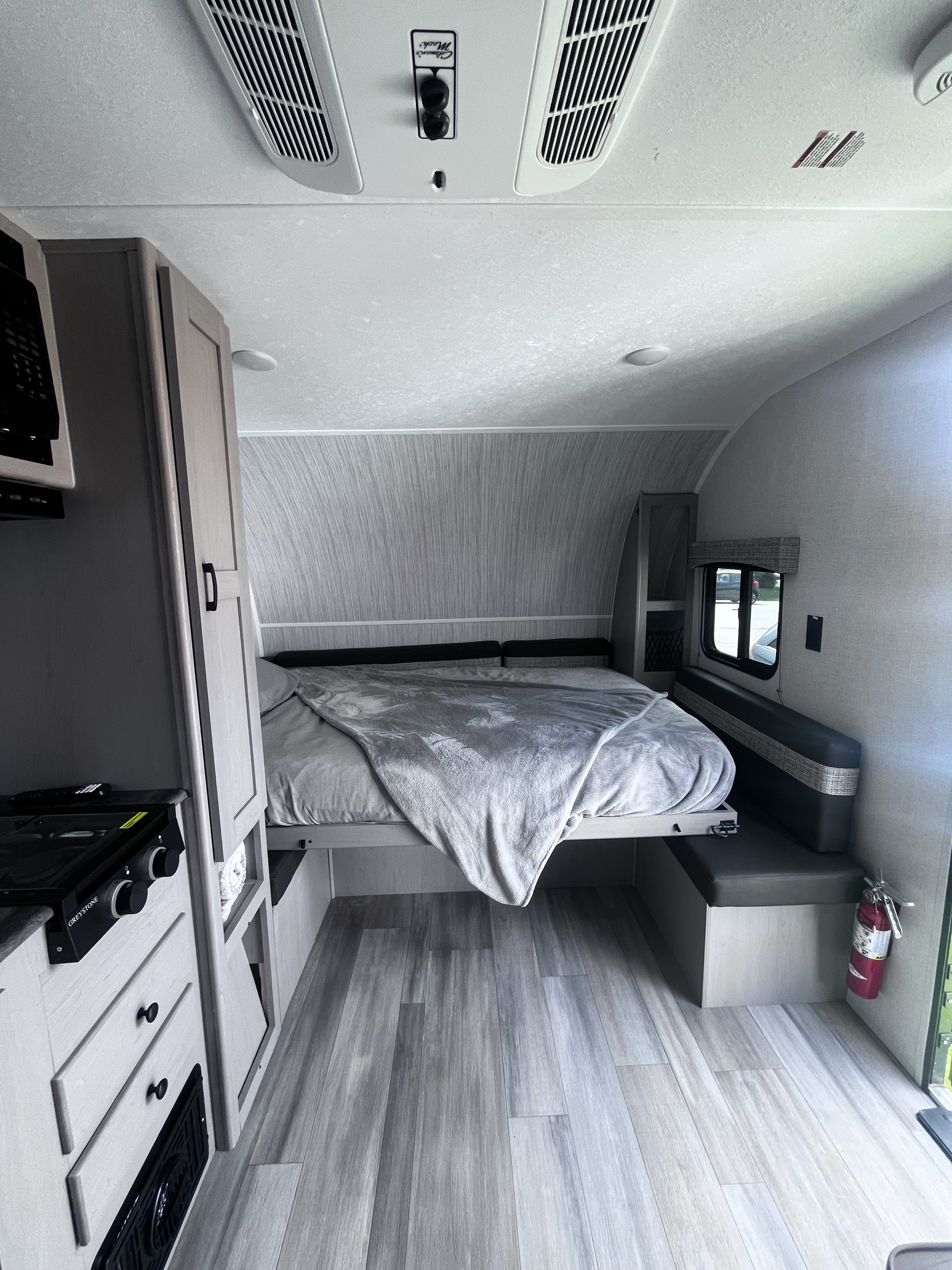 RV rental's inviting interior: features a comfy bed, compact kitchen, and dinette, all with light modern finishes.. Clipper 4K 2023