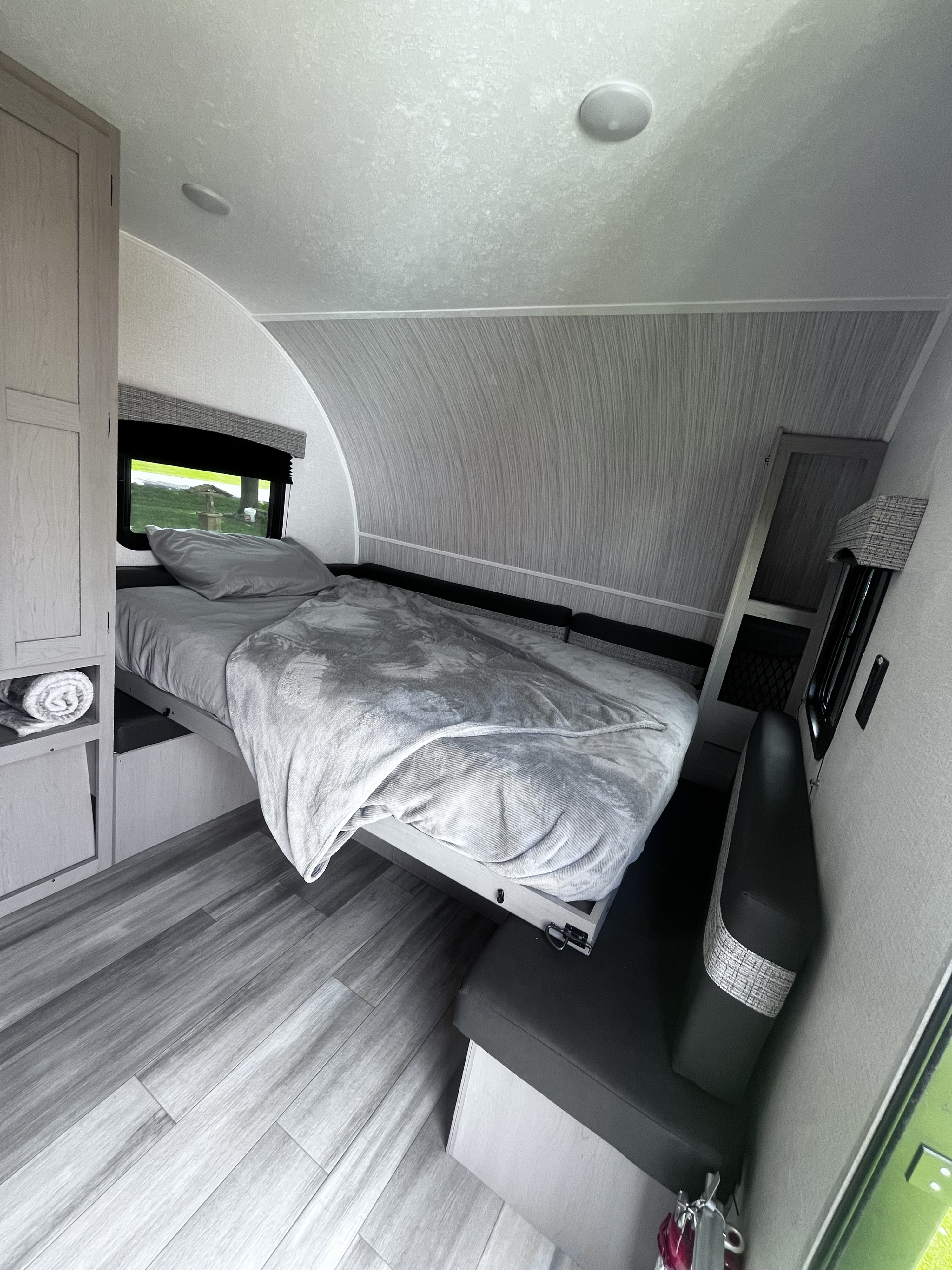 Cozy rv rental interior with a comfortable bed, compact seating, and wood-look flooring, ready for your next trip.. Clipper 4K 2023