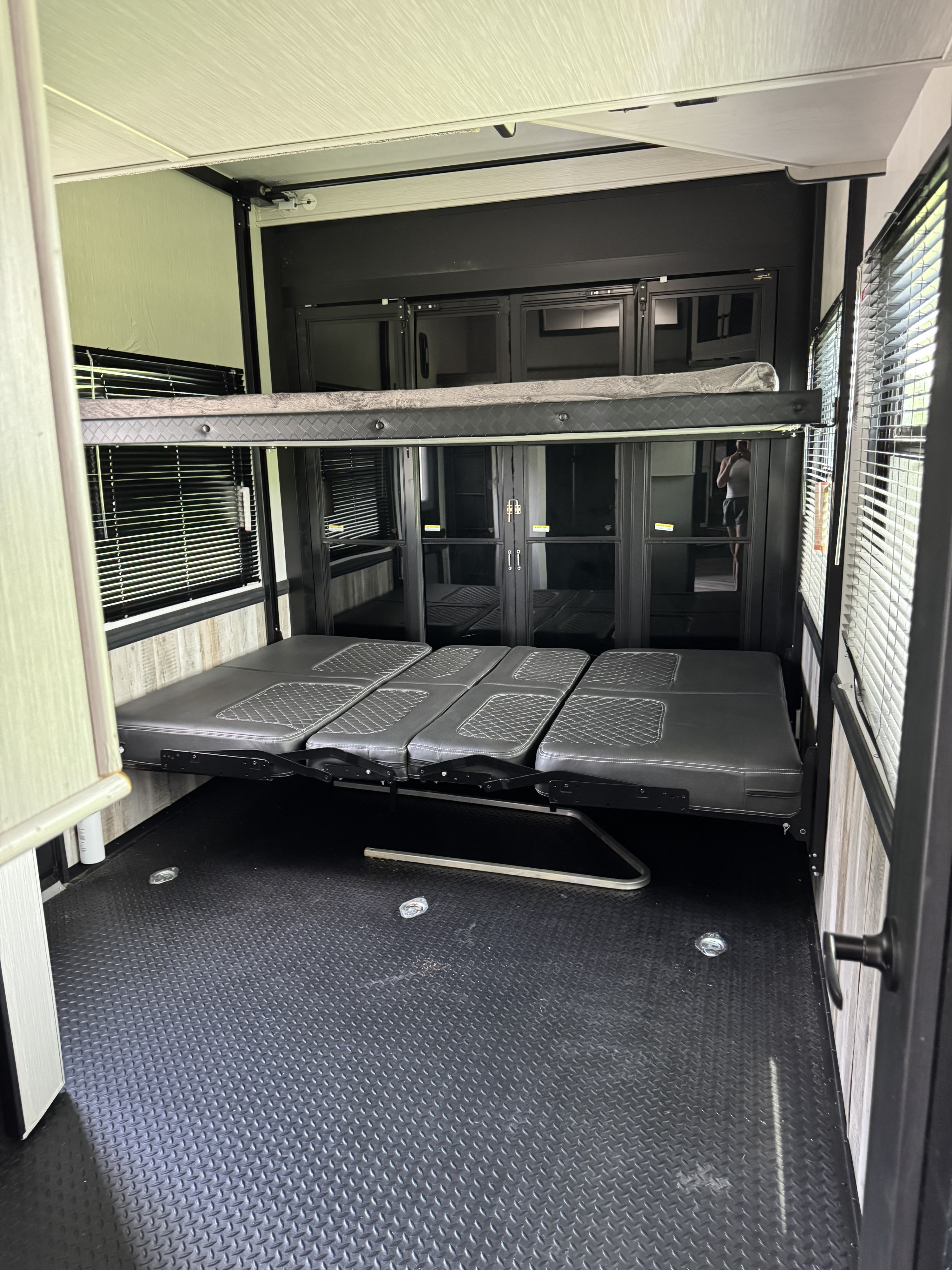 RV rental toy hauler garage showing adjustable bunk beds, seating, and rugged black floor.. Heartland Toyhauler 2022