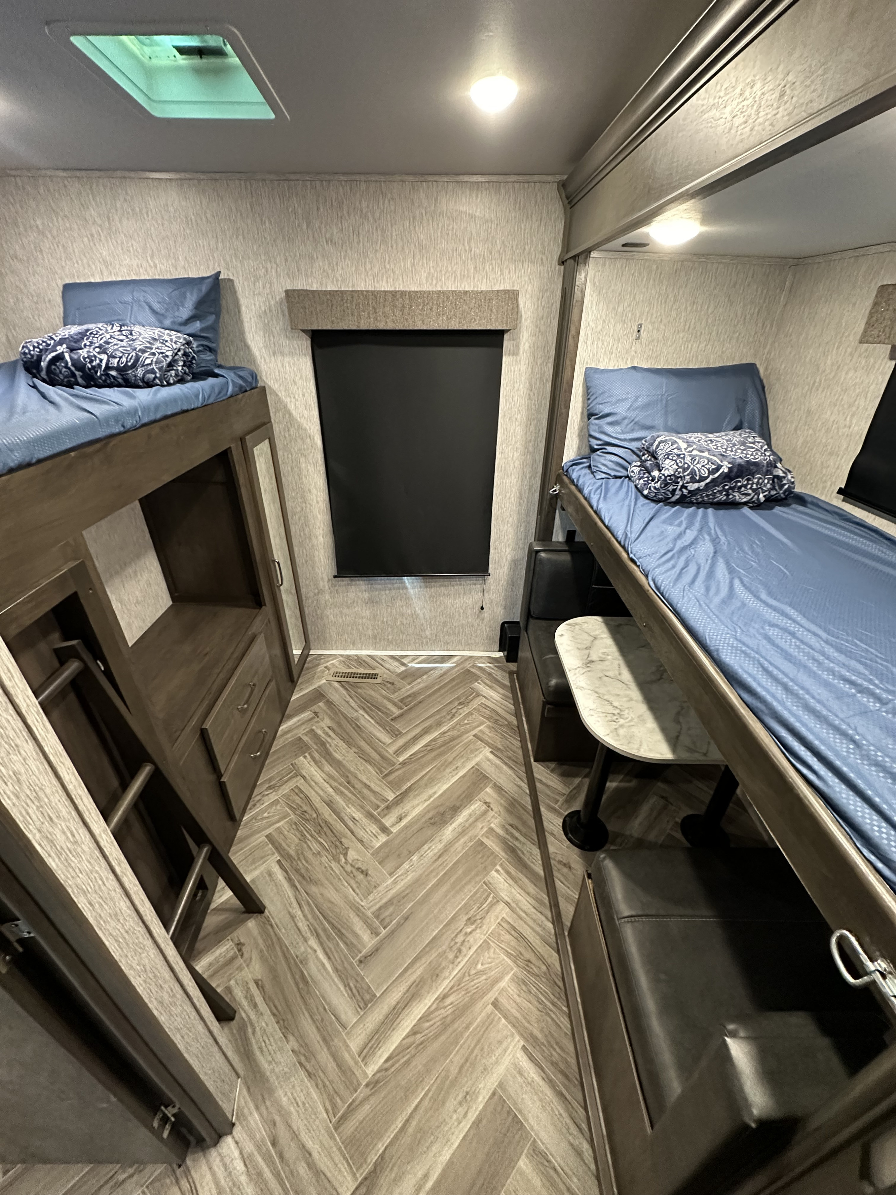 RV rental interior features a bunk room with two beds, storage, and herringbone flooring. Includes a dinette for comfort.. Astoria 1500 2021