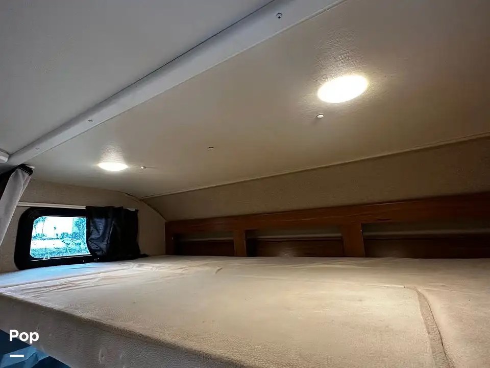 RV rental interior: Bright over-cab bunk bed with a comfortable mattress, window with black curtain, and LED lights.. Jayco Melbourne 2016