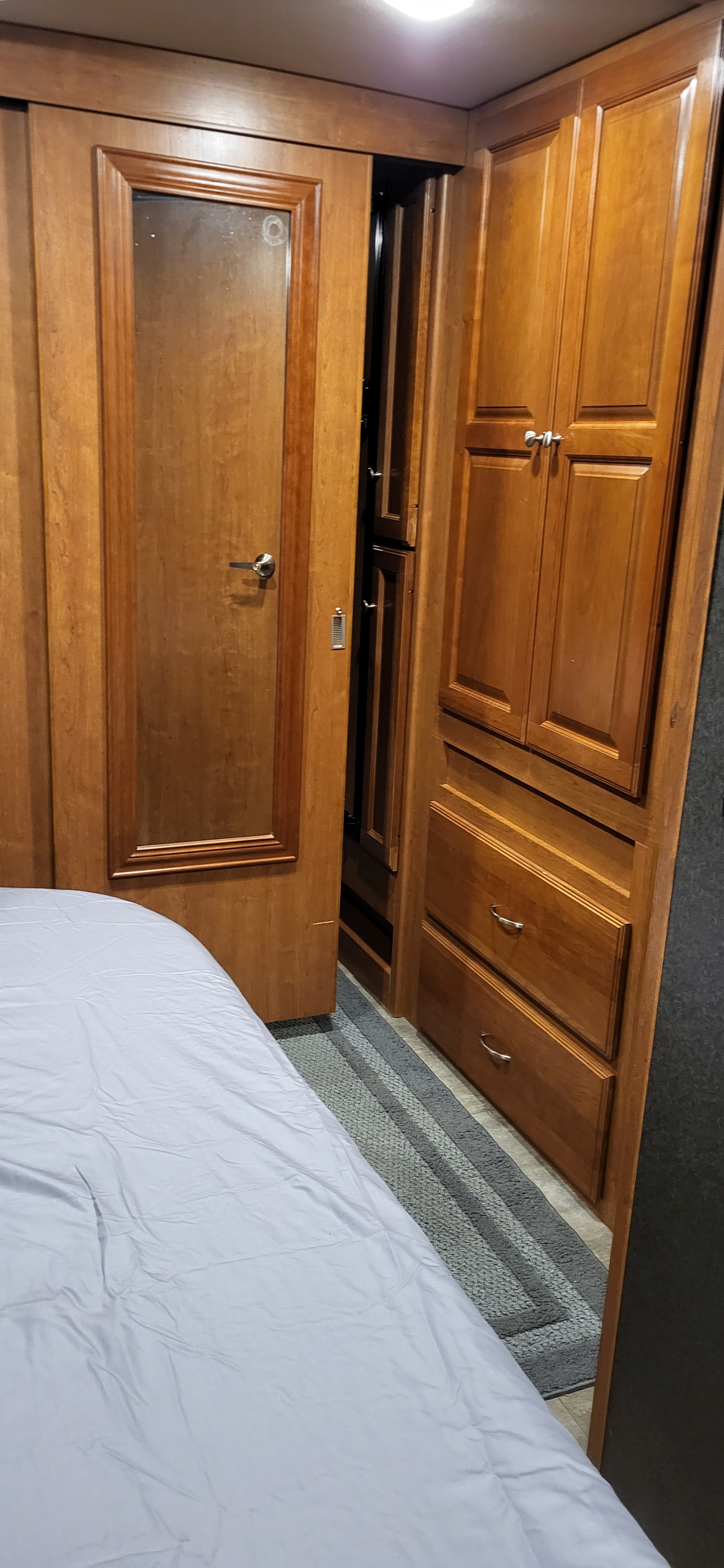 Cozy RV rental interior with a comfortable bed, wooden cabinets, and a door, showcasing practical storage solutions.. Winnebago Vista 2018