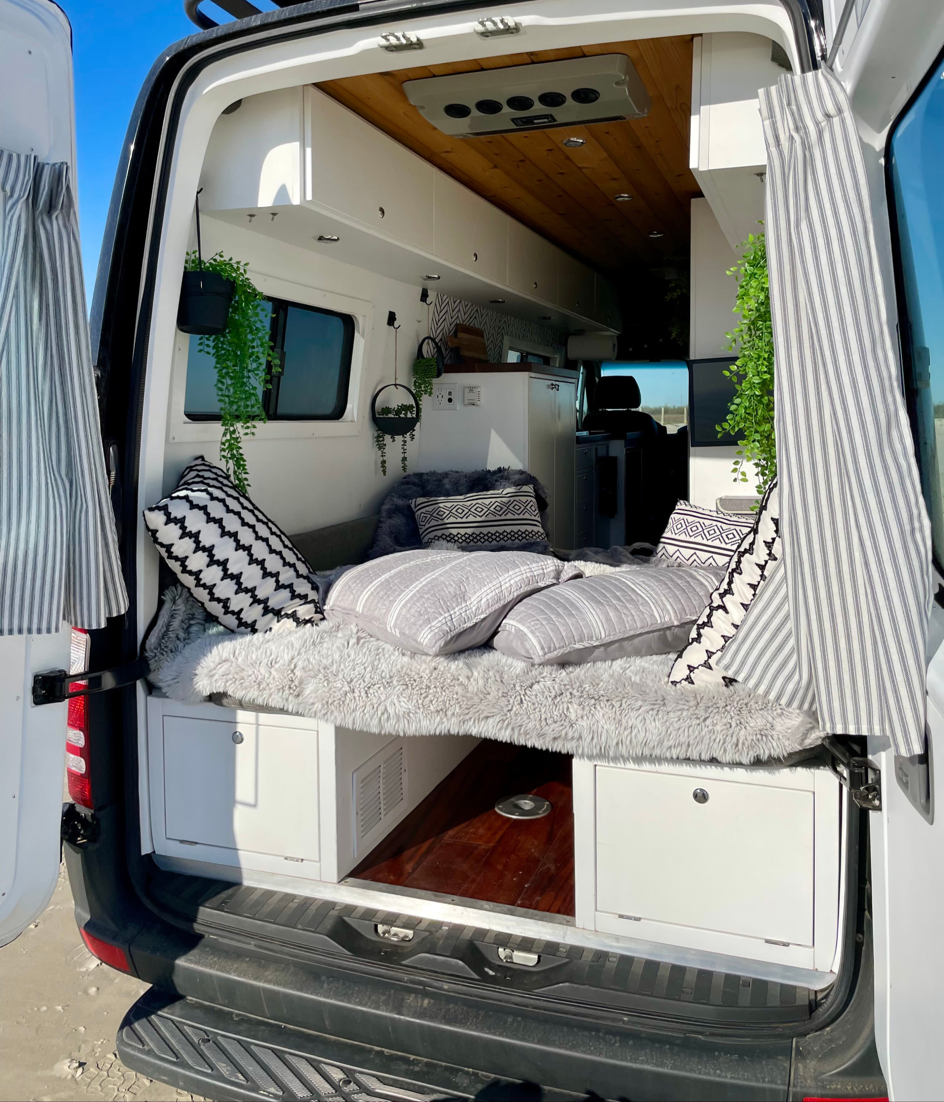 RV rental: Cozy camper van interior with bed, storage cabinets, and natural light from the open back doors.. Mercedes-Benz Sprinter 2016