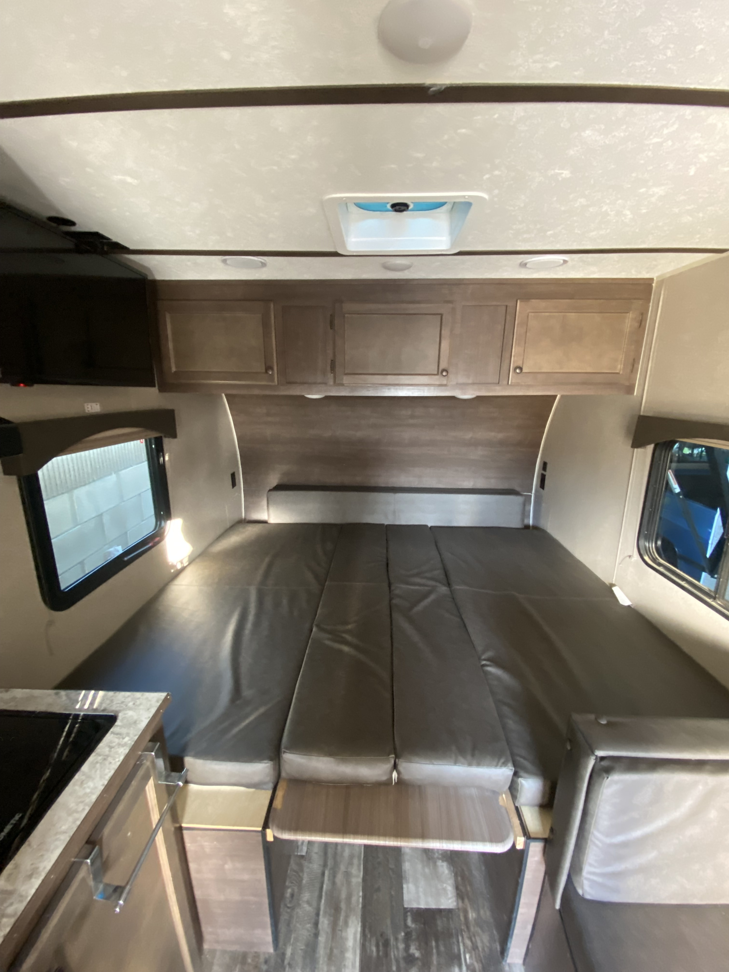 Cozy RV rental interior with a large, padded convertible bed, overhead storage, TV, and kitchenette for comfortable travels.. Sun Lite Classic CCH 2022