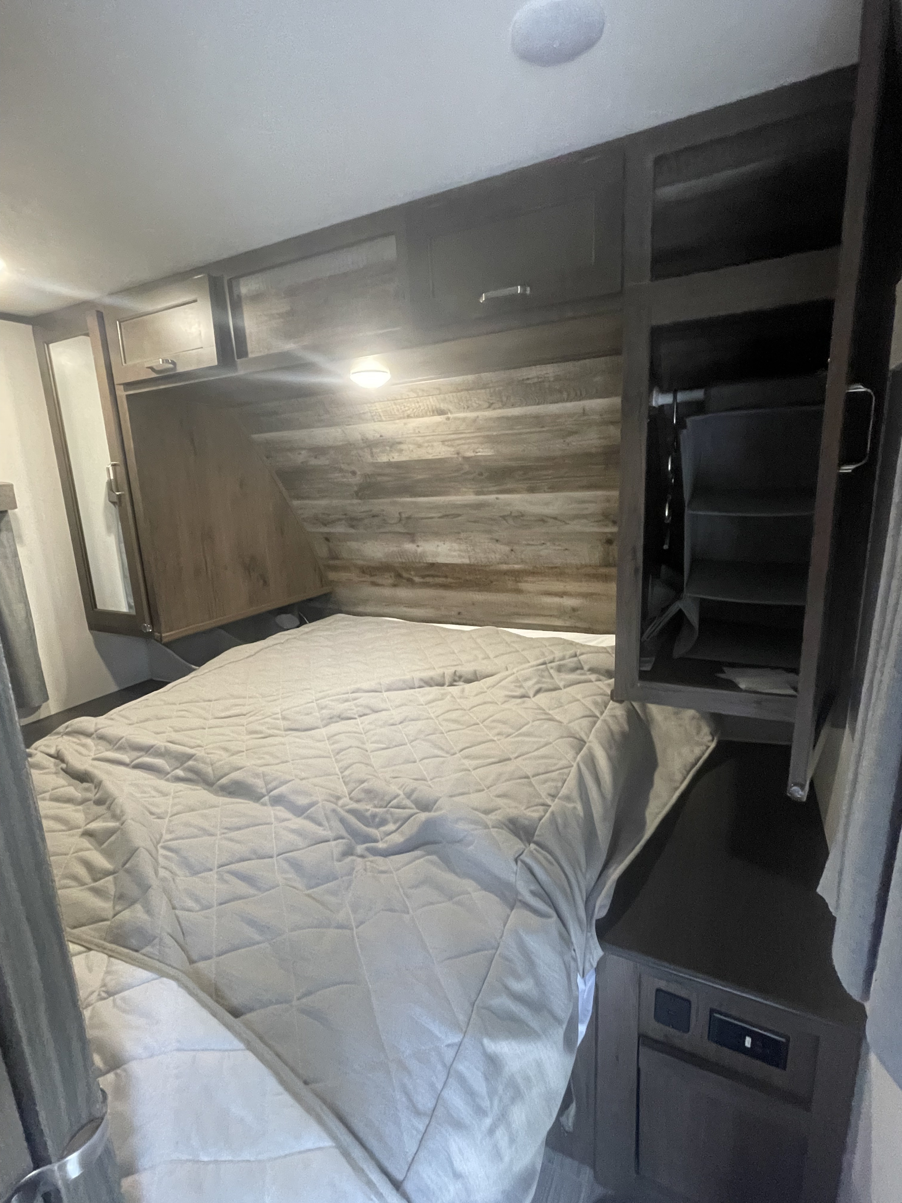 Comfortable RV rental bedroom featuring a quilted bed, overhead storage, and a built-in closet.. Keystone RV Passport SL 2021