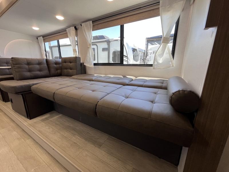 This modern RV rental features a multi-functional brown sofa, converting from spacious seating to a large sleeping area.. Wildwood X-Lite 25ICE 2025