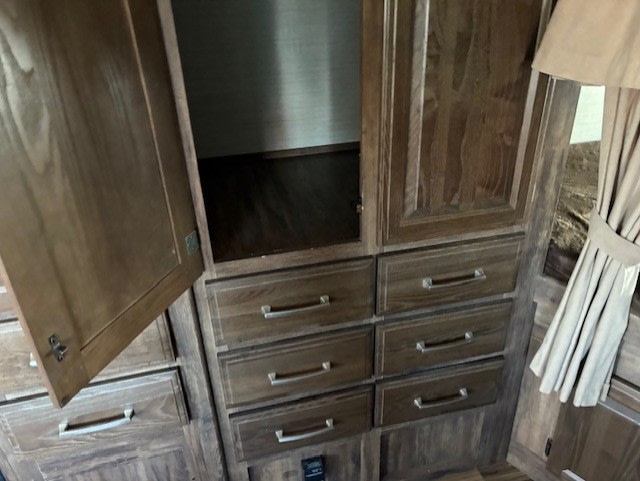 RV rental interior featuring wooden storage cabinets, an open closet, and multiple drawers with silver pulls.. Keystone RV Cougar 28RBS 2016