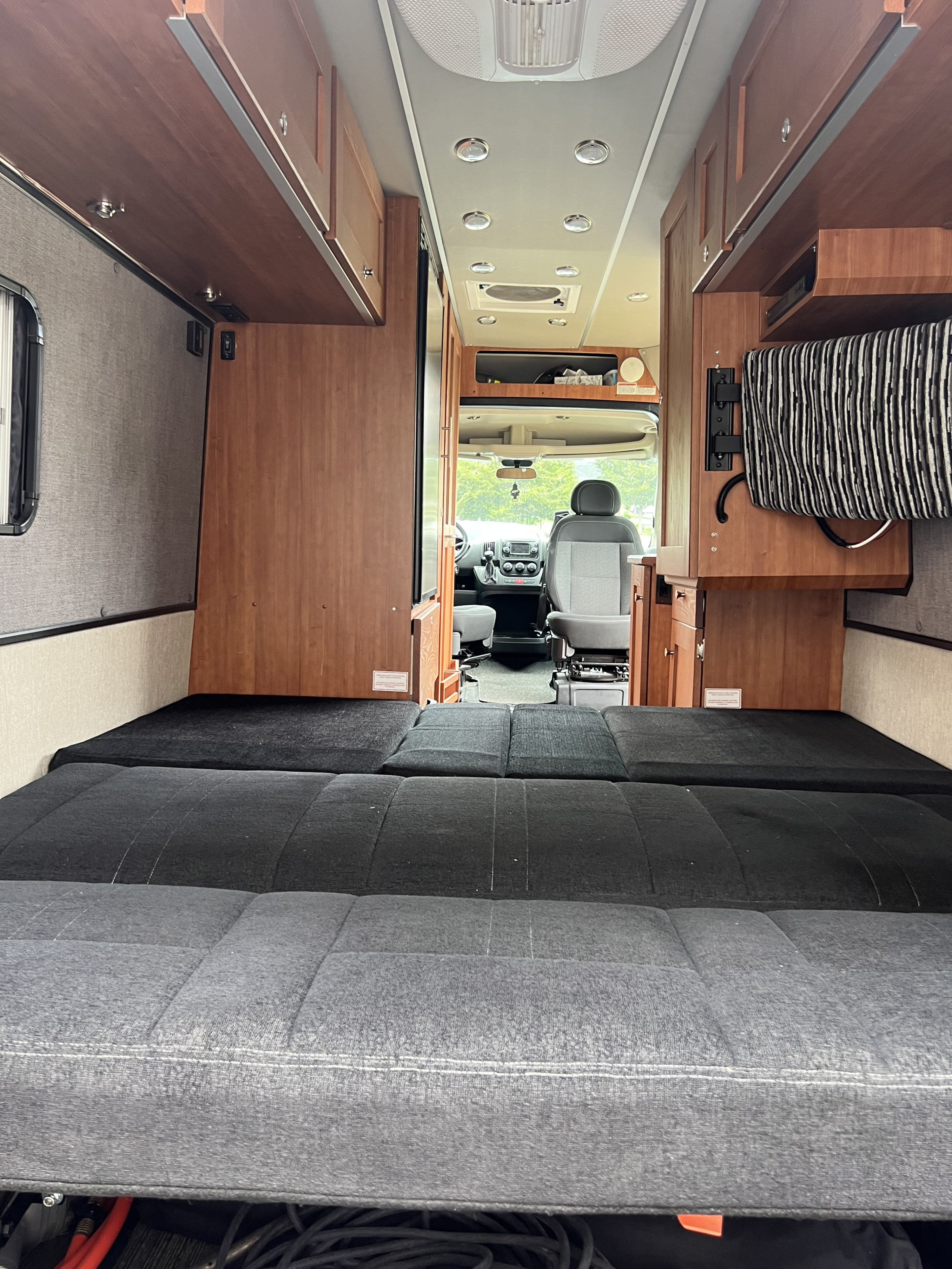Cozy RV rental interior with modular bed, wood cabinets, and front cabin view. Ready for your next trip.. Roadtrek Roadtrek Class B 2018