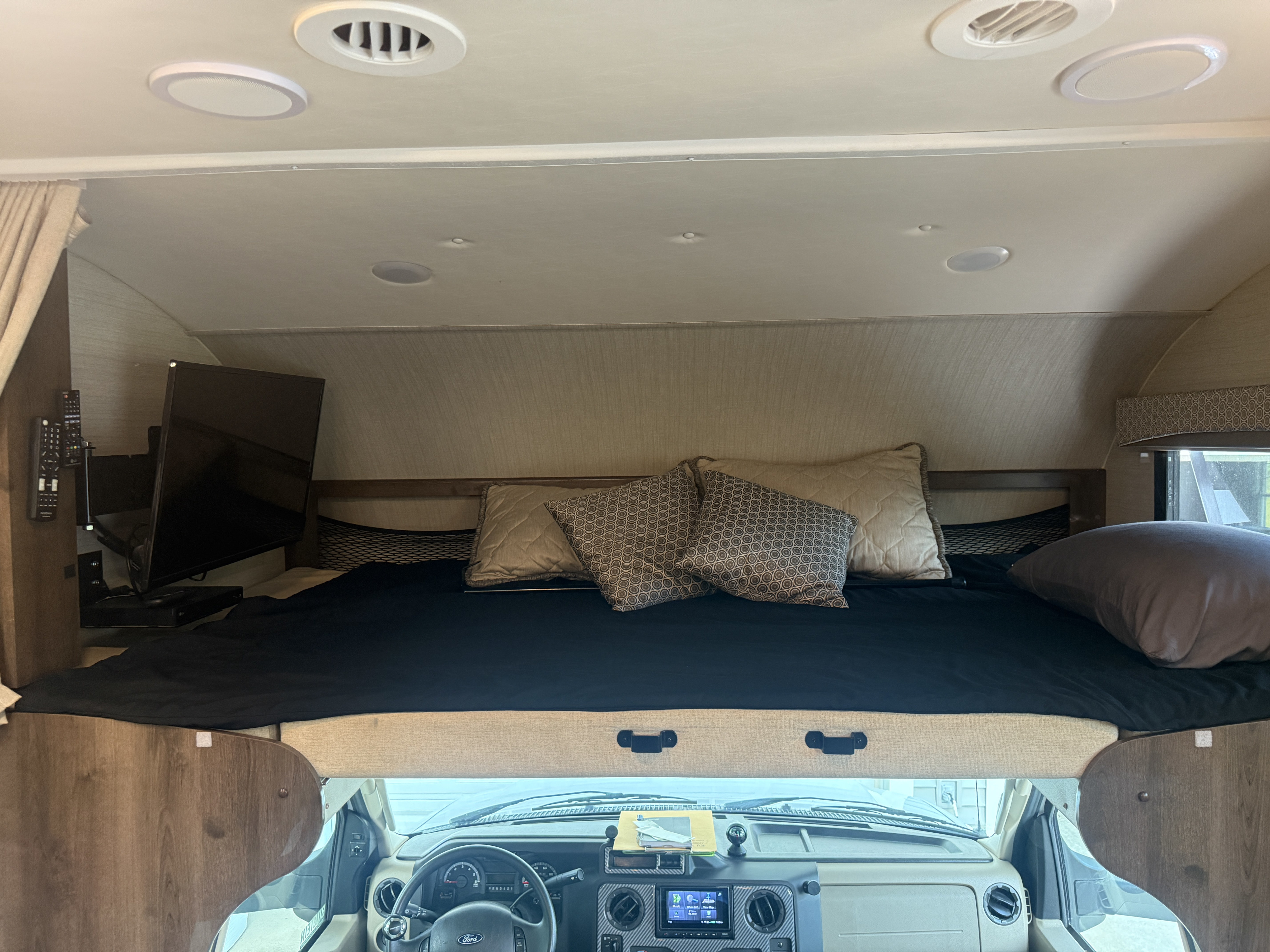 Spacious cab-over bunk bed in this RV rental, featuring a cozy sleeping area, TV, and interior lights.. Jayco Greyhawk 2018