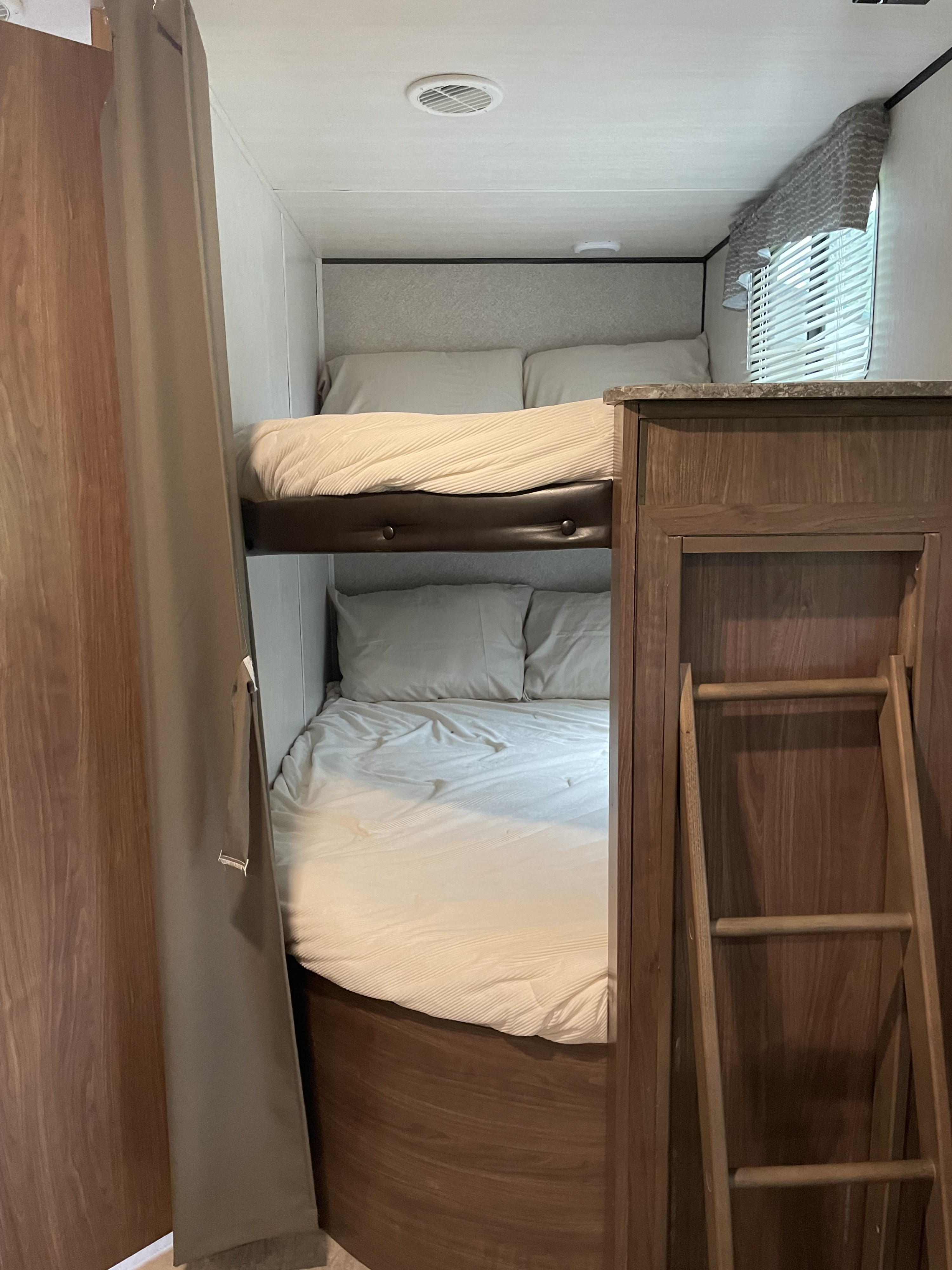 Cozy bunk beds with light linens and a ladder in this RV rental's sleeping area.. Heartland RVs Trail Runner 2018