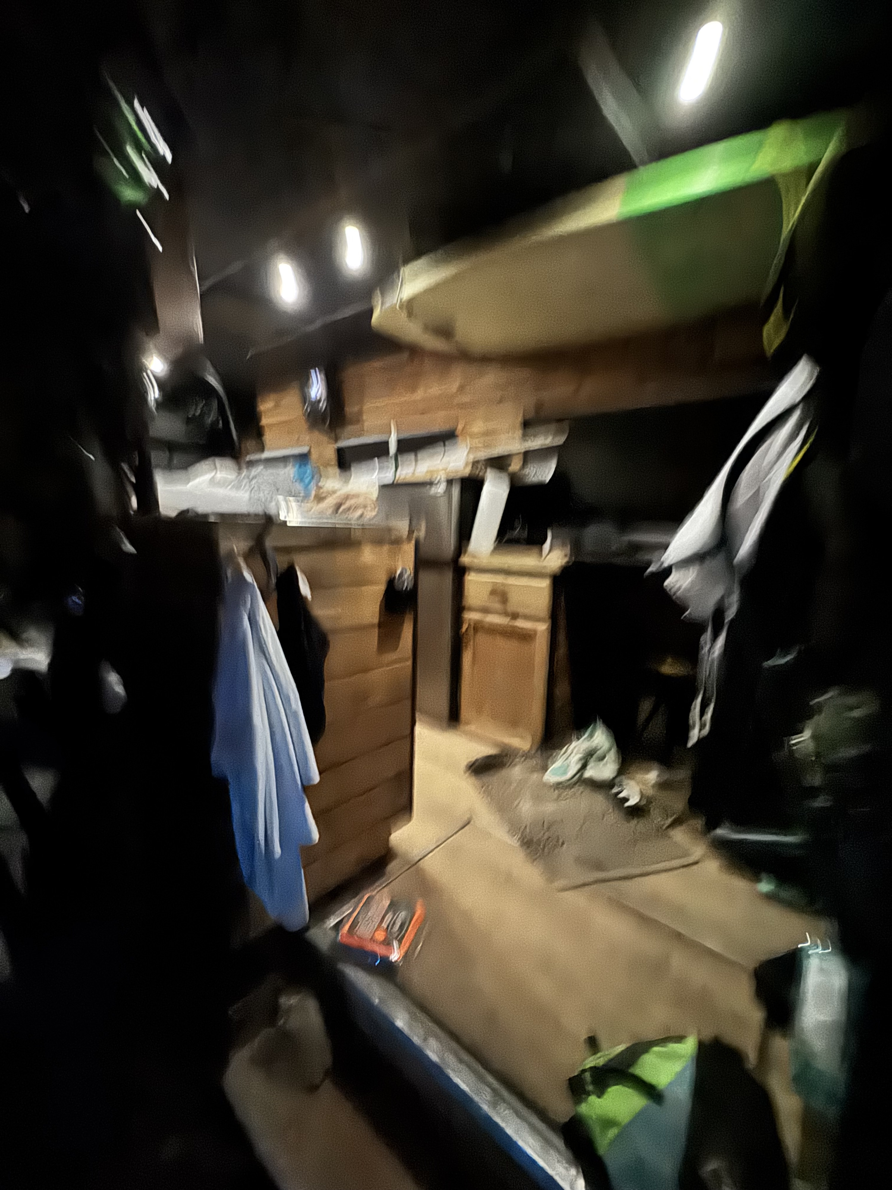 Dimly lit RV rental interior. Features a paddleboard stored on the ceiling, hanging clothes, and built-in wooden storage.. Mercedes-Benz Sprinter 2500 2015