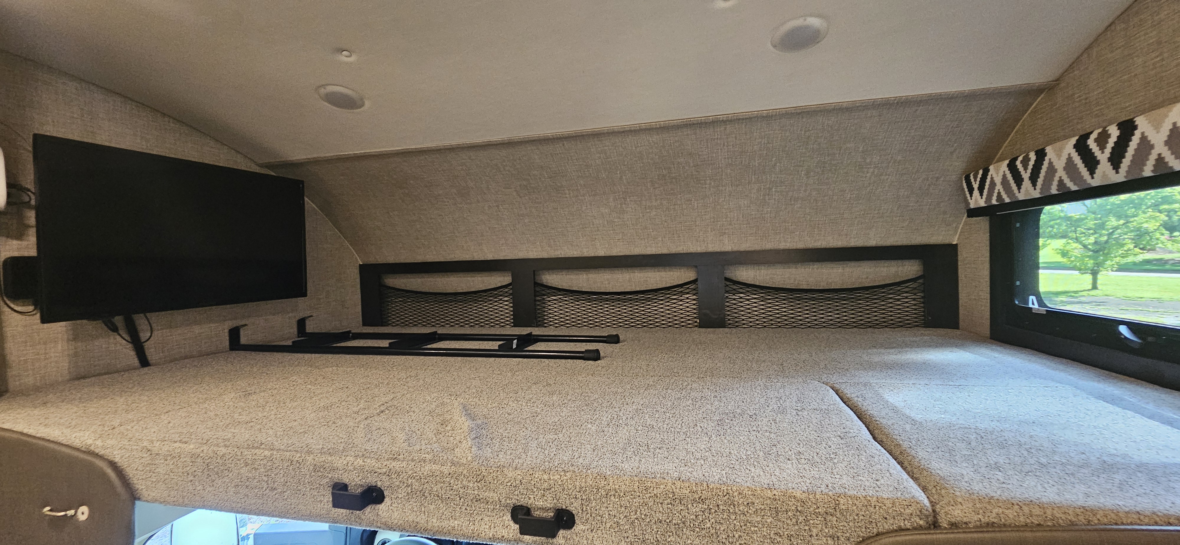 This RV rental features a comfortable cab-over bunk bed, mounted TV, storage nets, and a scenic window view.. Jayco Greyhawk 2022