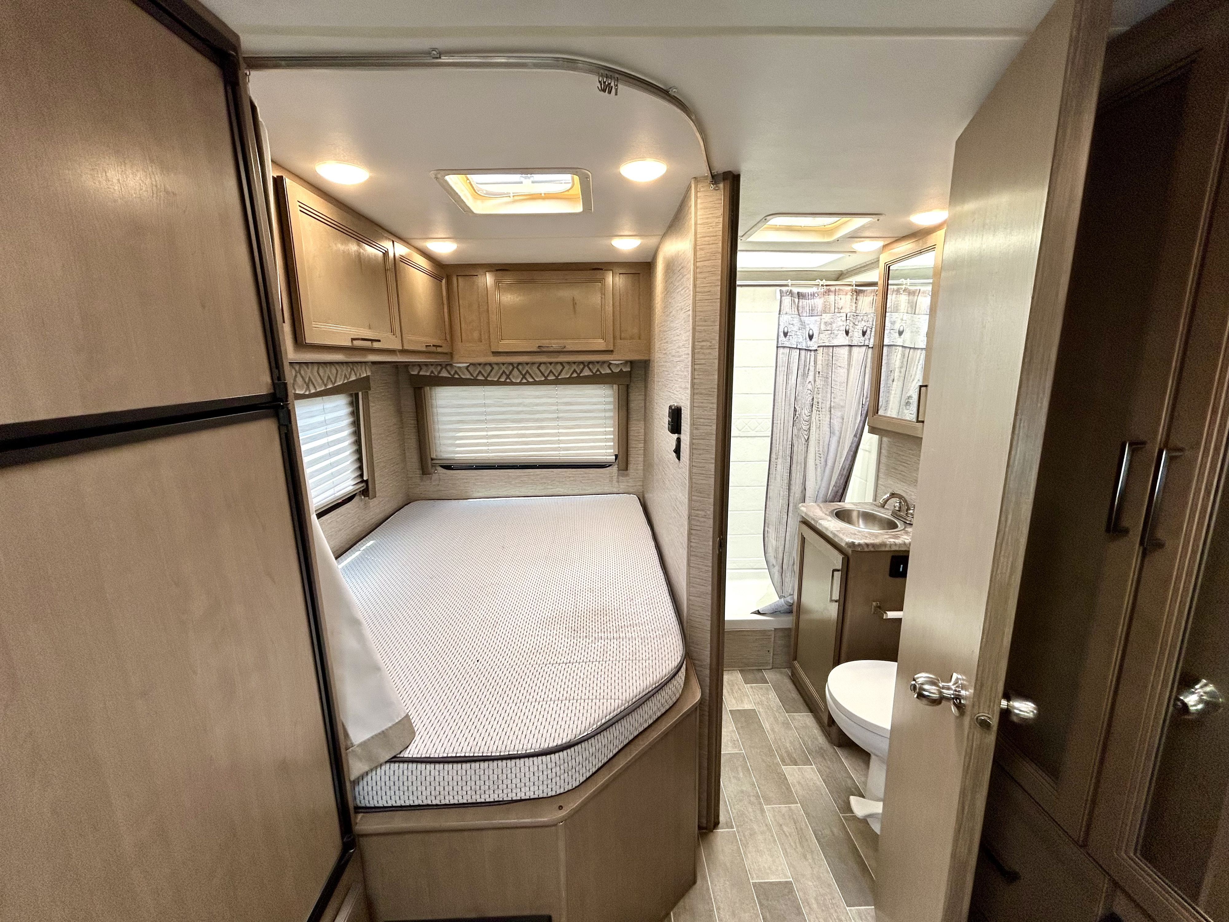 Inside this RV rental: a compact bedroom with a built-in bed, and a small bathroom with a sink, toilet, and shower.. Thor Quantum SE 2021