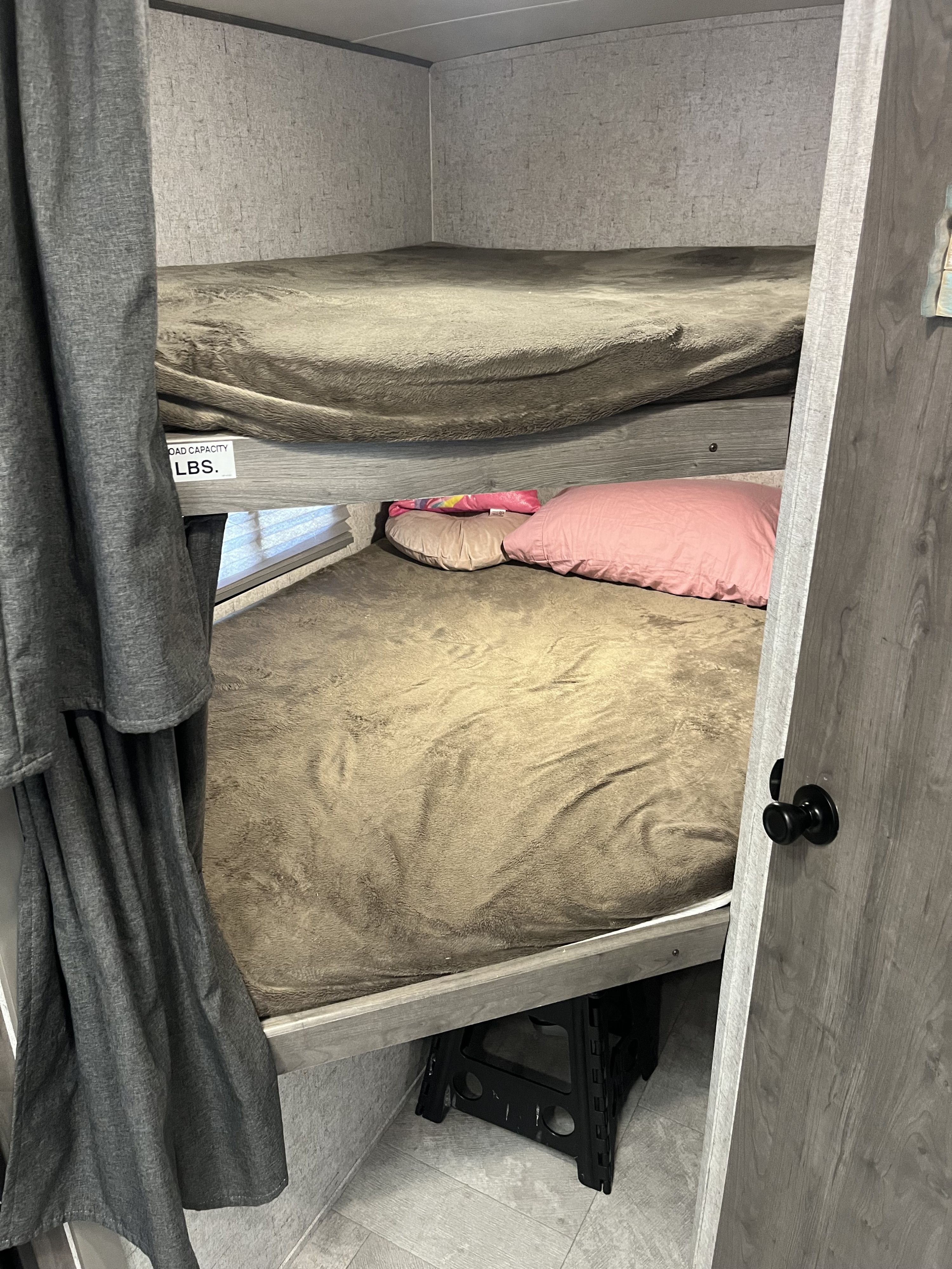 RV rental bunk beds: Two cozy bunks, one above the other, with soft blankets, pink pillows, and a step stool.. Coachmen Apex Nano 2019