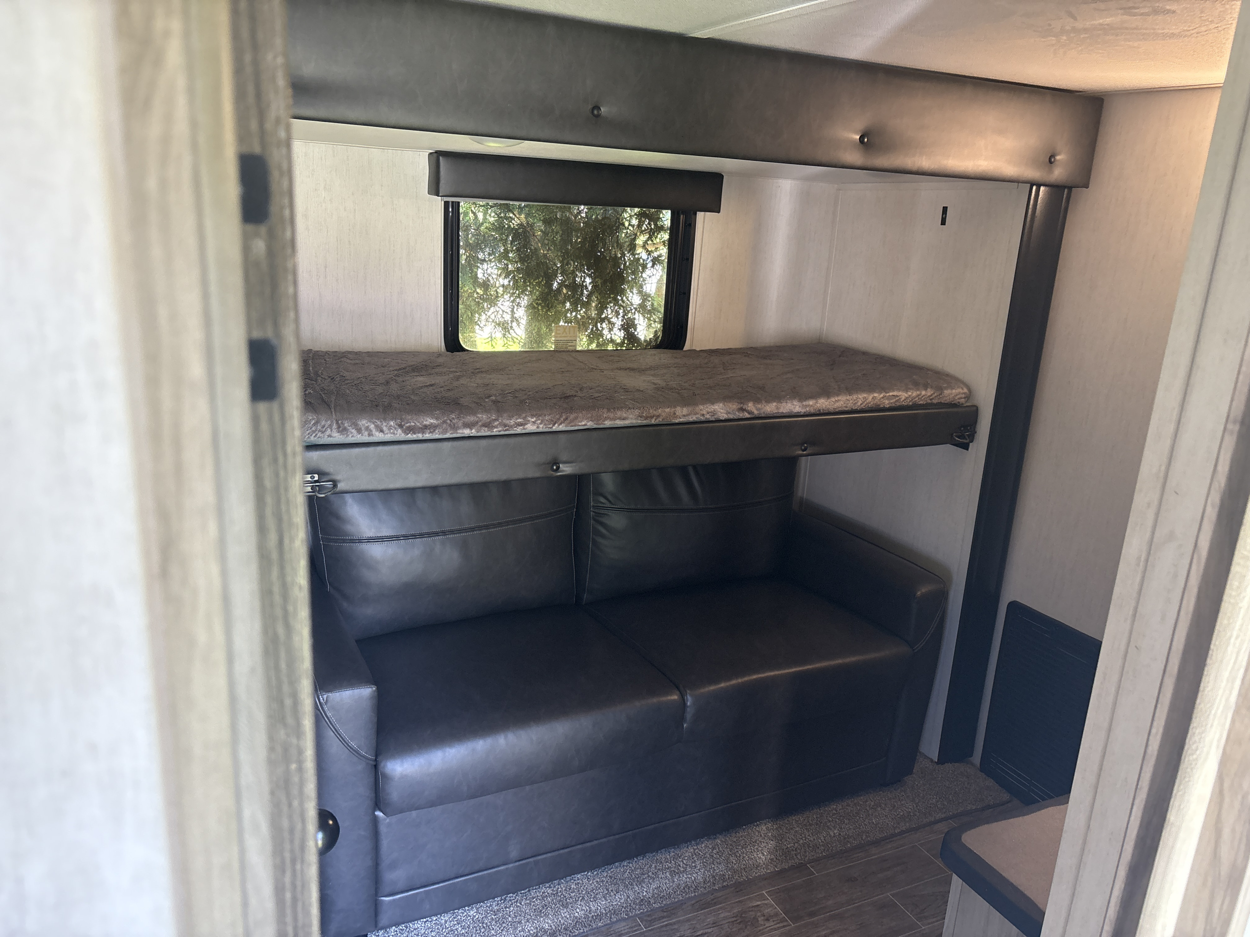 RV rental featuring a bunk bed over a sofa, providing versatile sleeping and seating space inside the unit.. Forest River Cherokee Arctic Wolf 2022