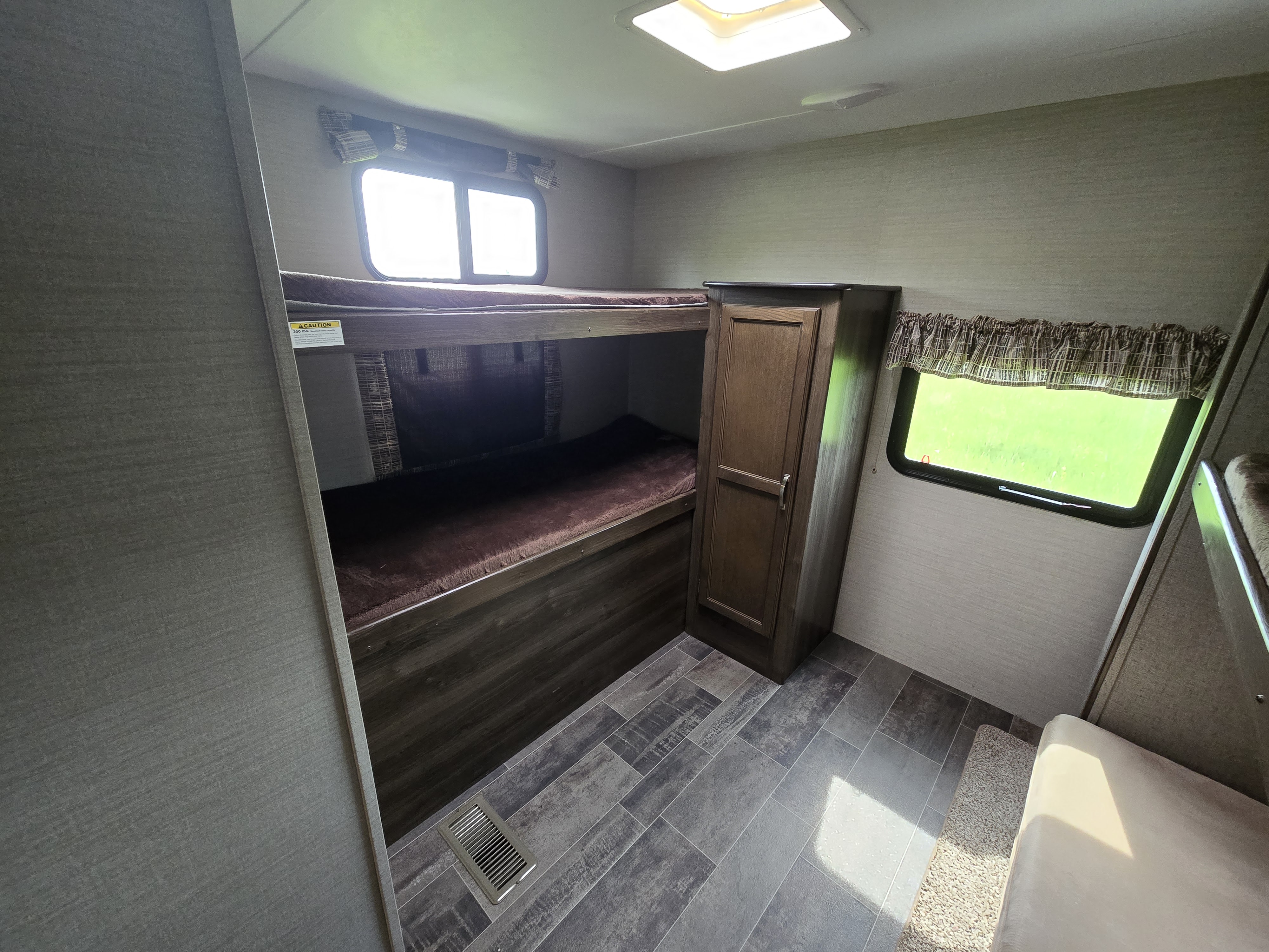 RV rental interior features bunk beds, a wardrobe, and windows with green views. Great for family adventures.. Keystone RV Bullet Ultra Lite 2018