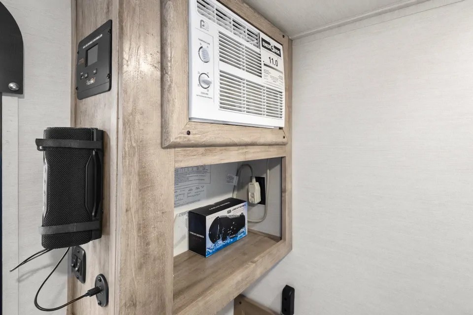 RV rental amenities: AC unit, system control panel, and speaker with charging port in a modern RV interior.. GulfStream Trail Boss 1090K 2025