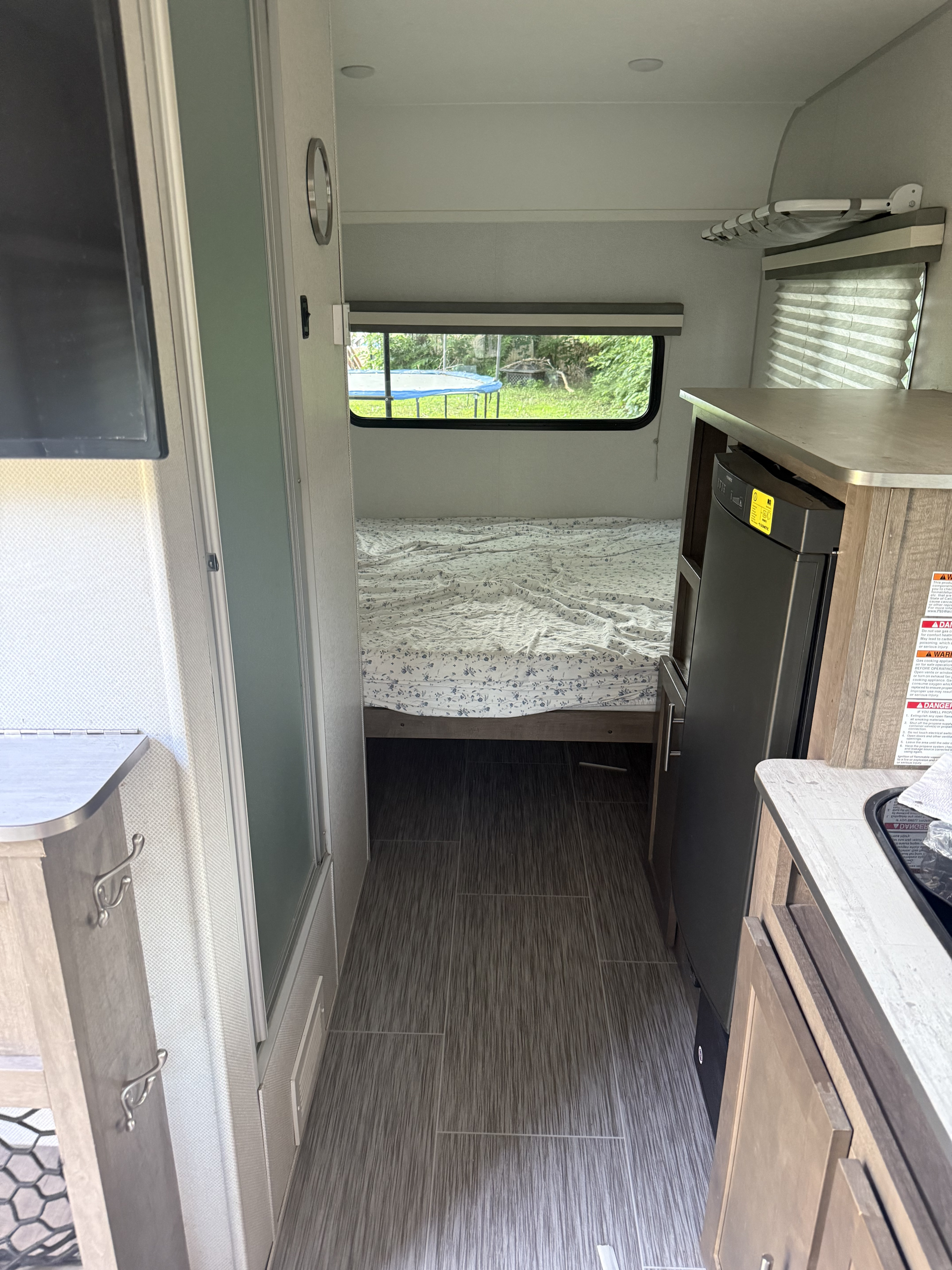 An rv rental interior shows the compact kitchen on the right, leading to a cozy bedroom. Perfect for travel living.. No Boundaries 16 2019