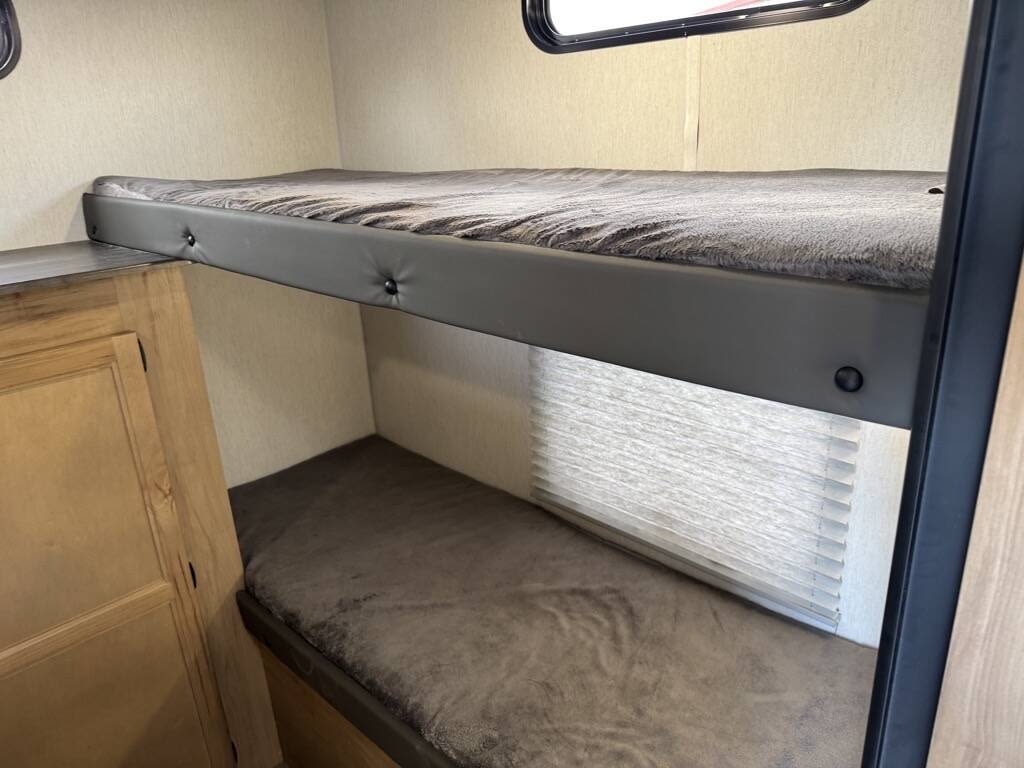 Explore this RV rental's cozy interior, featuring comfortable bunk beds, window blinds, and built-in storage. Ideal for travel.. Forest River Cherokee Grey Wolf 2023
