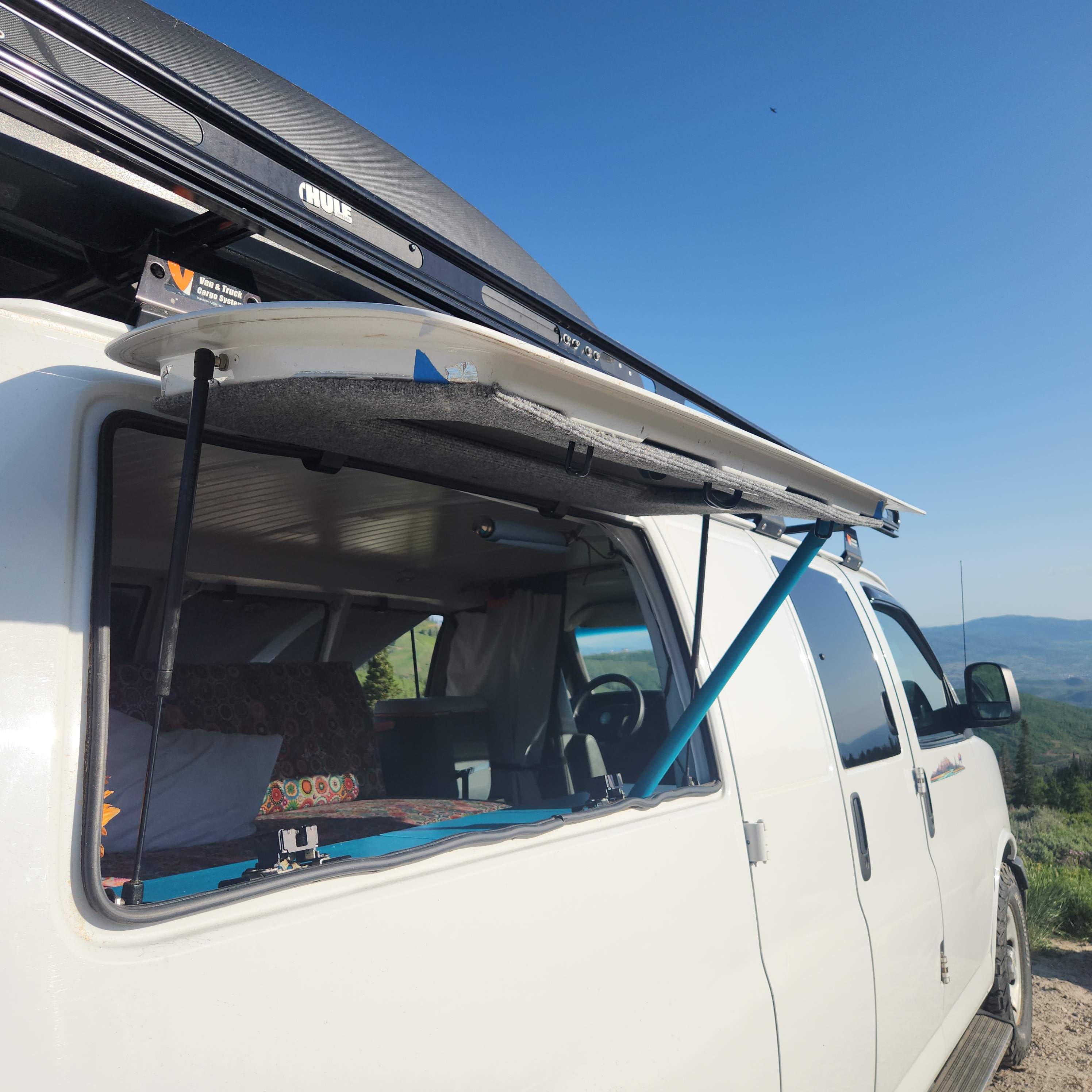 Experience van life with an RV rental! White conversion van with open window overlooking scenic mountains. Perfect for adventure.. Chevrolet Express 1500 AWD 2014