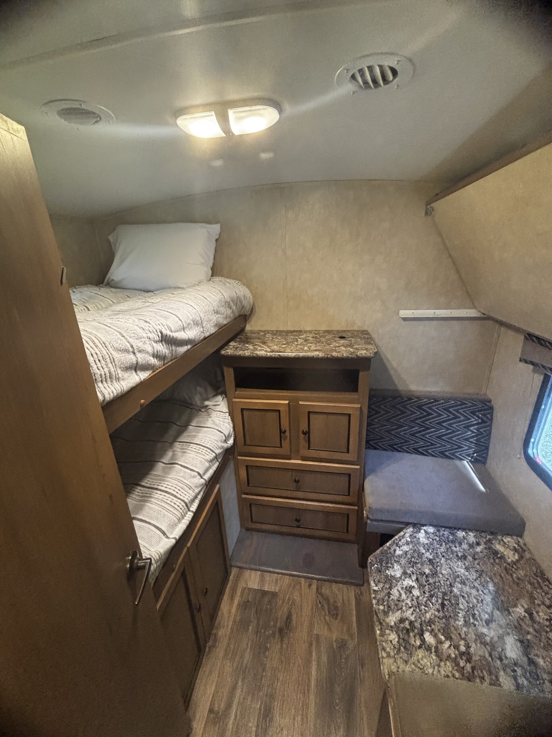 Cozy RV rental interior showcasing bunk beds, wood-look storage, and a practical dinette with stone-look counters.. Cruiser RV Shadow Cruiser 2015