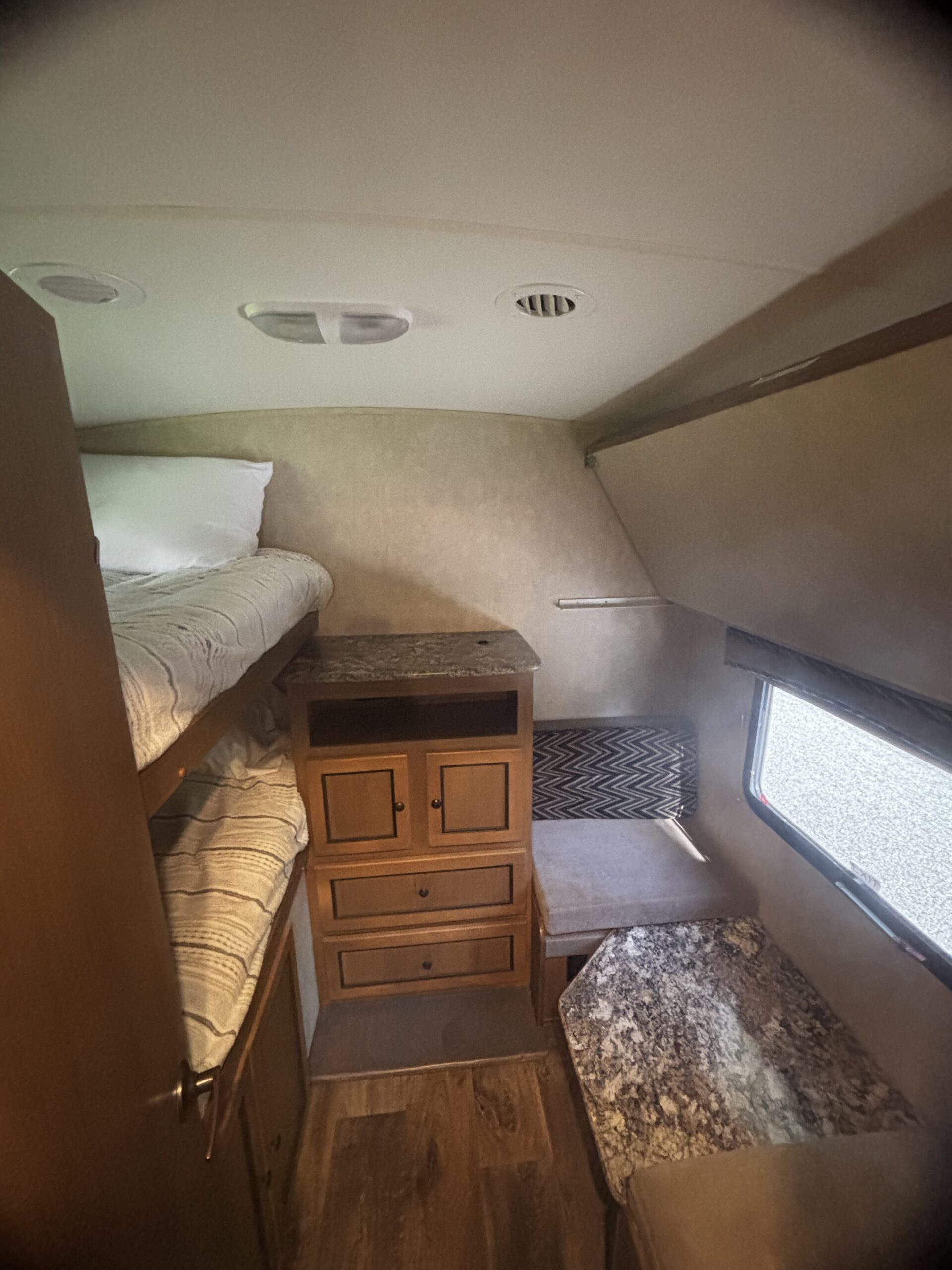 This RV rental bunk and dinette area features wood-look flooring, a storage cabinet, and a window for natural light.. Cruiser RV Shadow Cruiser 2015
