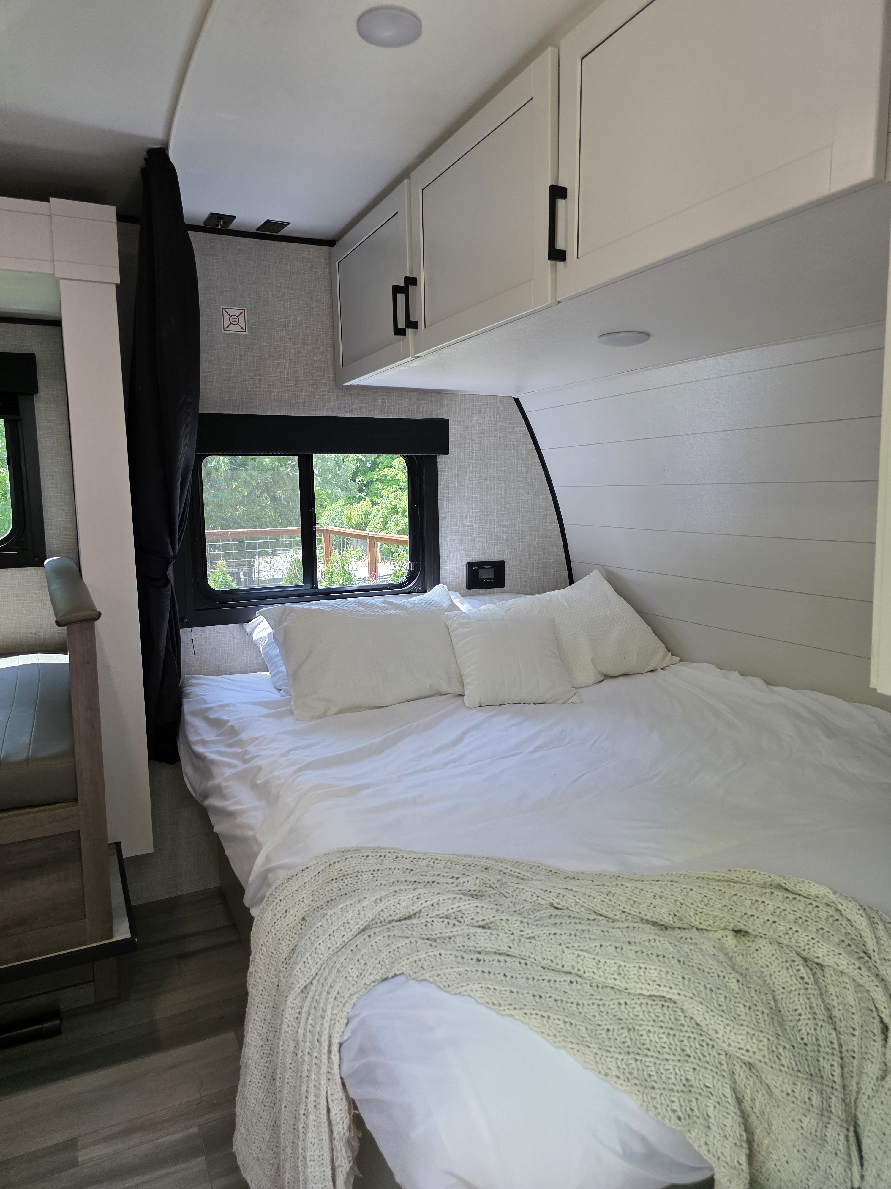 Cozy RV rental bedroom with a comfy white bed, bunk, and bright window views. Modern and clean.. Highland Ridge Open Range MOAB 2025