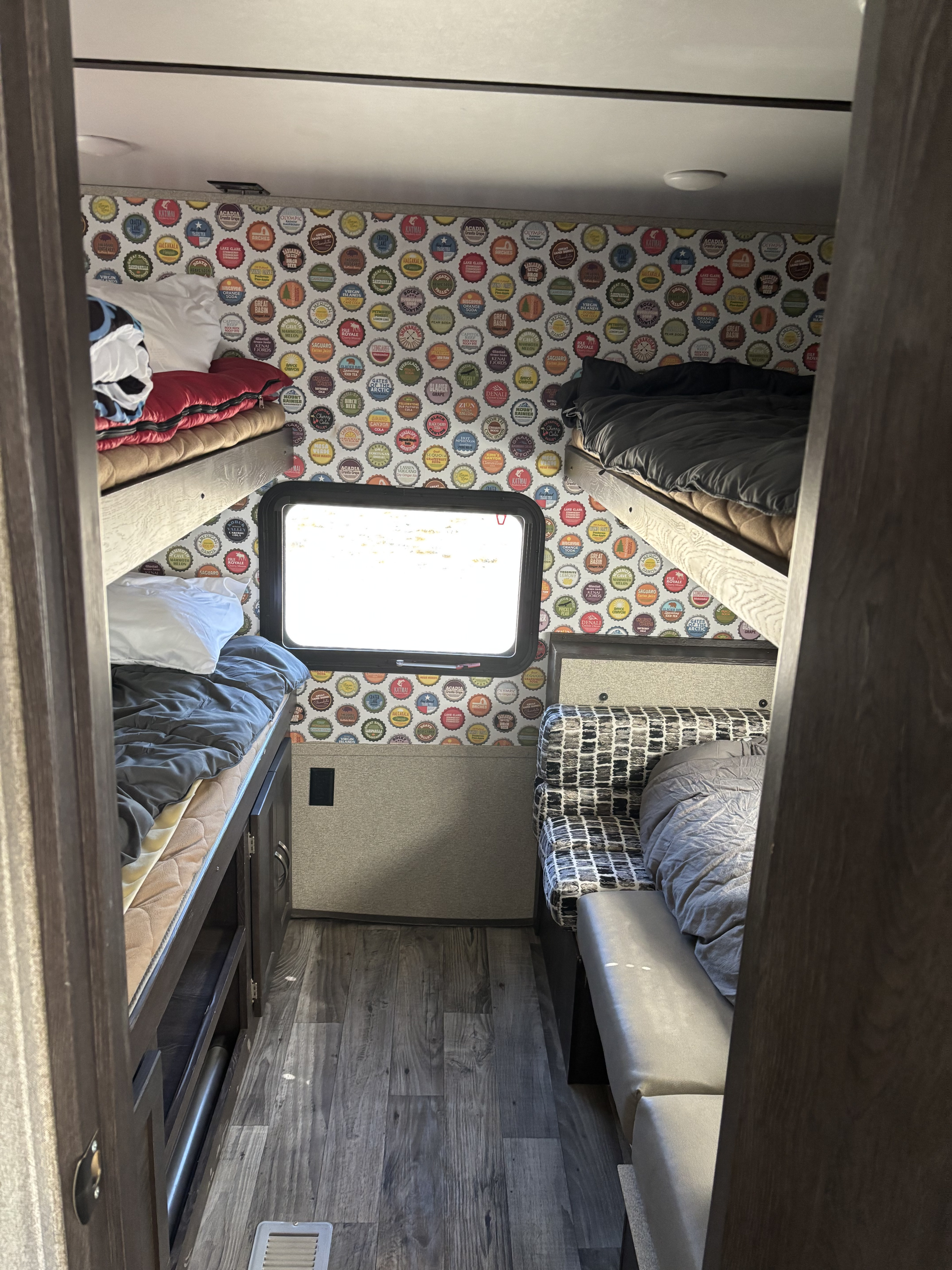 This RV rental features a cozy interior with bunk beds, a window, and a distinctive national park bottle cap wall for travel.. Crossroads RV Zinger 2020