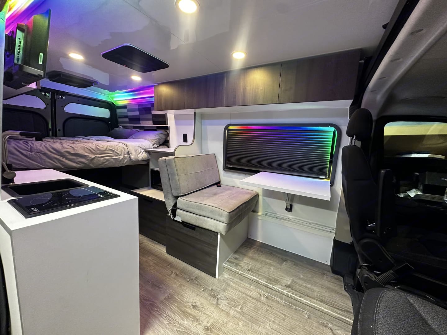 Modern RV rental interior: cozy bed, kitchen, seating, and vibrant LED lighting in a spacious camper van setup.. Dodge Promaster 2500 2022