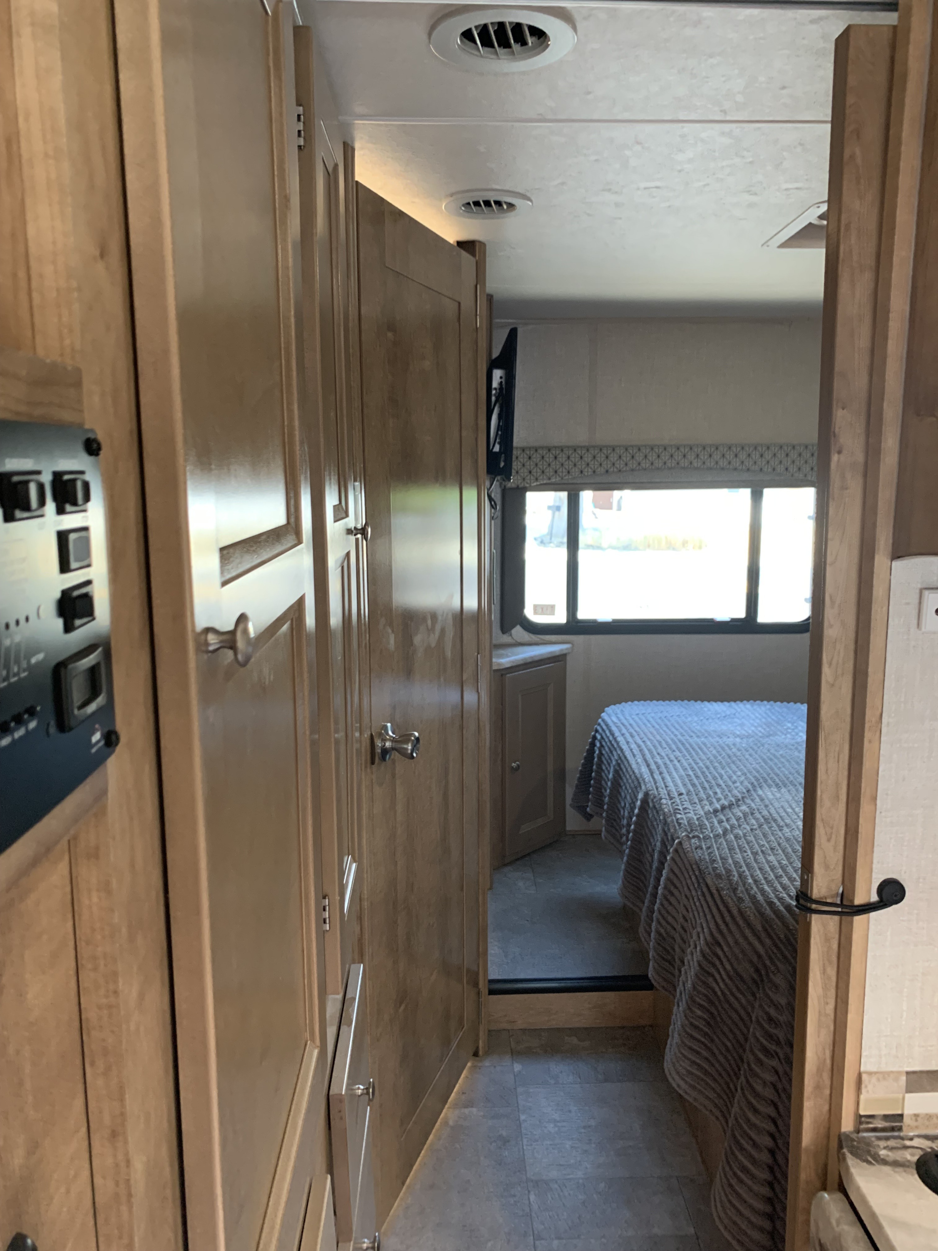 RV rental interior showcasing bedroom with bed and window, plus functional cabinetry and control panel.. Forest River Coachmen Leprechaun 2020