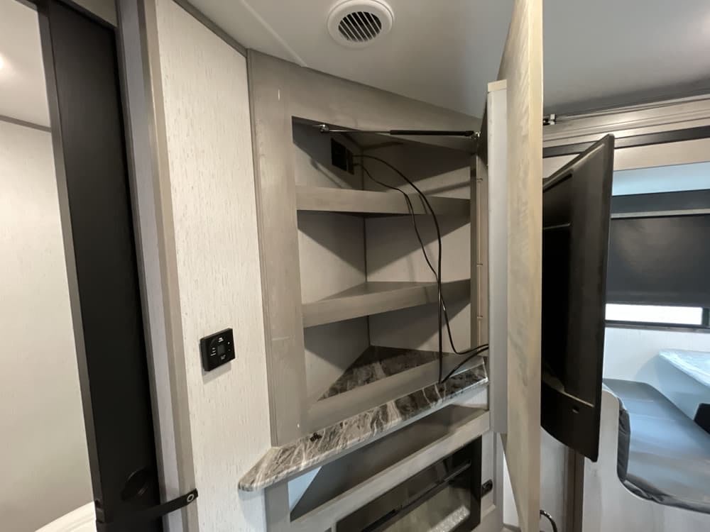 Swing-out TV and shelves in this RV rental's entertainment center, optimizing space for your travel comfort.. Dutchmen Kodiak Ultra Lite 2022